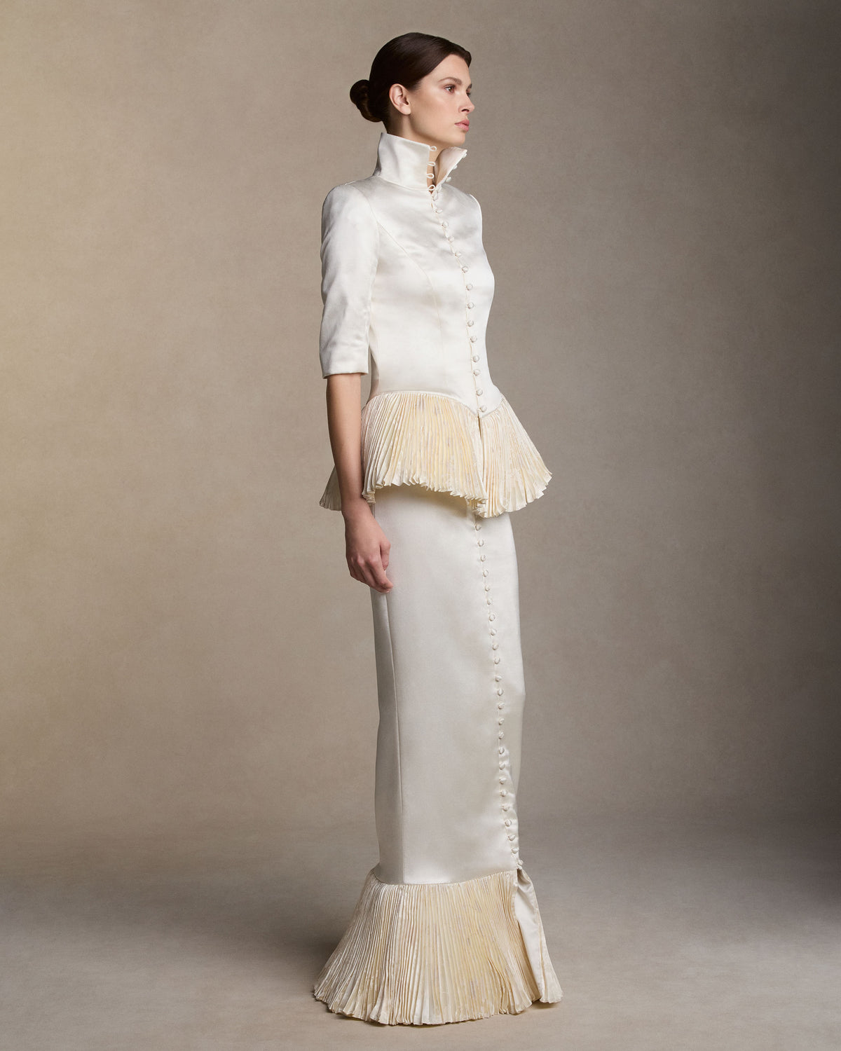 Tailored jacket in silk wool satin with shaped seams finished with a sharp pleated peplum in pigment-printed, hand-painted silk wool. Center front covered button closure.Styled with Ulli skirt