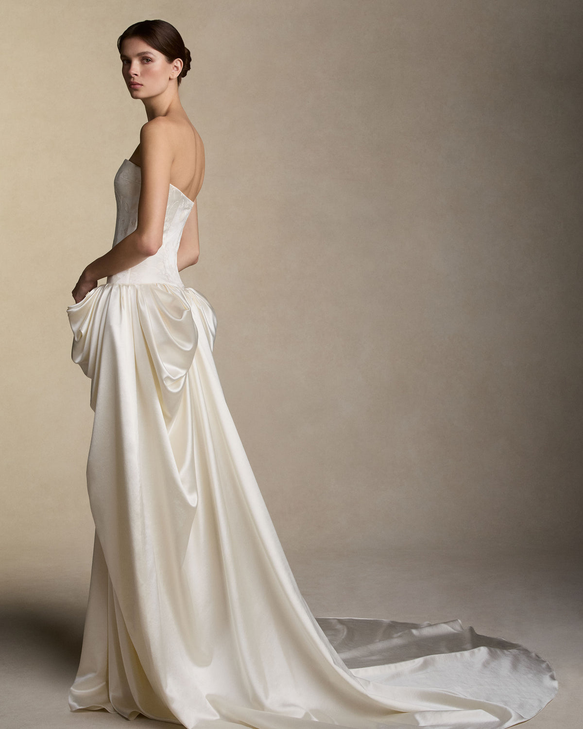 Pigment printed and hand painted silk wool strapless gown. Drop waist structured bodice releases into a sculptural yet soft skirt drape cascading into a soft train. Structured internal bustier with lace up corset and double zip bustier for added structure.