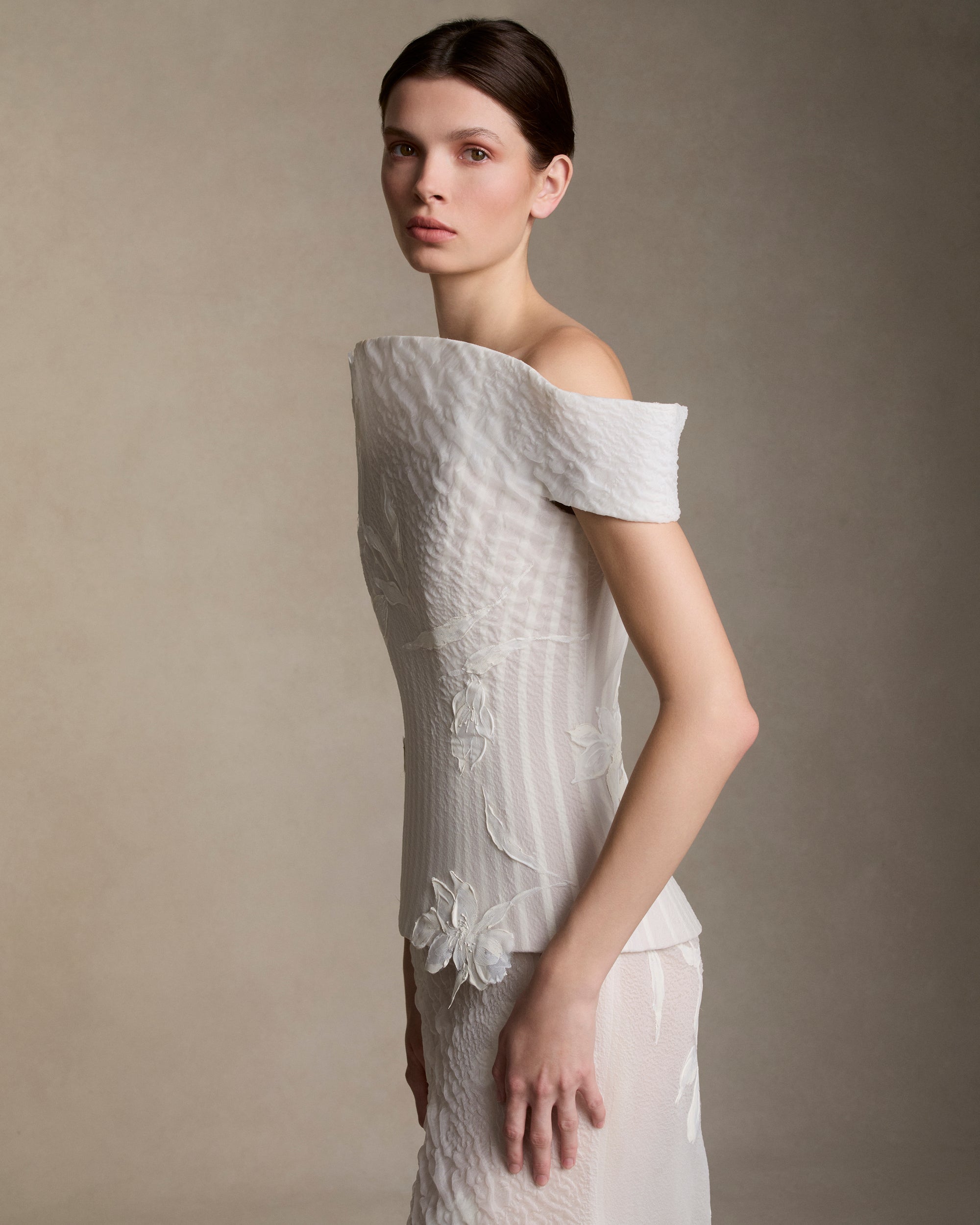 Textured cloqué organza structured bustier with hand painted iris appliques and grosgrain boning detail throughout. Elongated flared neckline molds into a structured cap sleeve as it peels away from the body. Boned internal bustier, internal grosgrain belt and invisible zip closure at center back.Styled with Dylan skirt