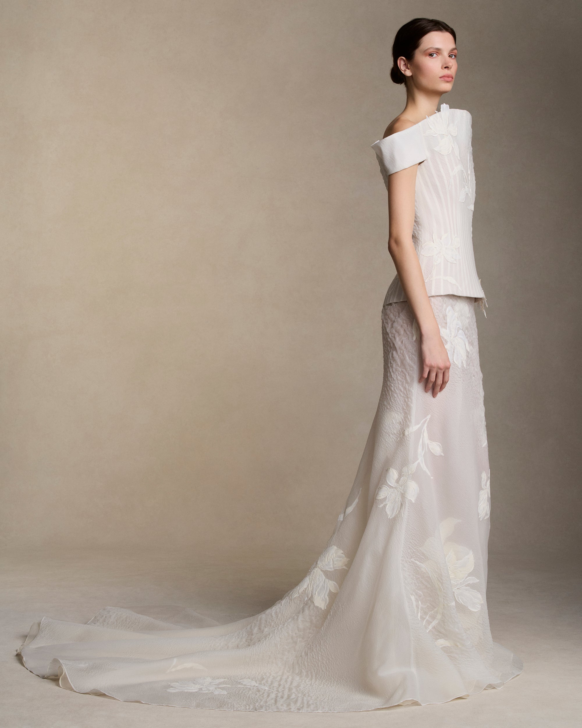 Textured cloqué organza structured bustier with hand painted iris appliques and grosgrain boning detail throughout. Elongated flared neckline molds into a structured cap sleeve as it peels away from the body. Boned internal bustier, internal grosgrain belt and invisible zip closure at center back.Styled with Dylan skirt