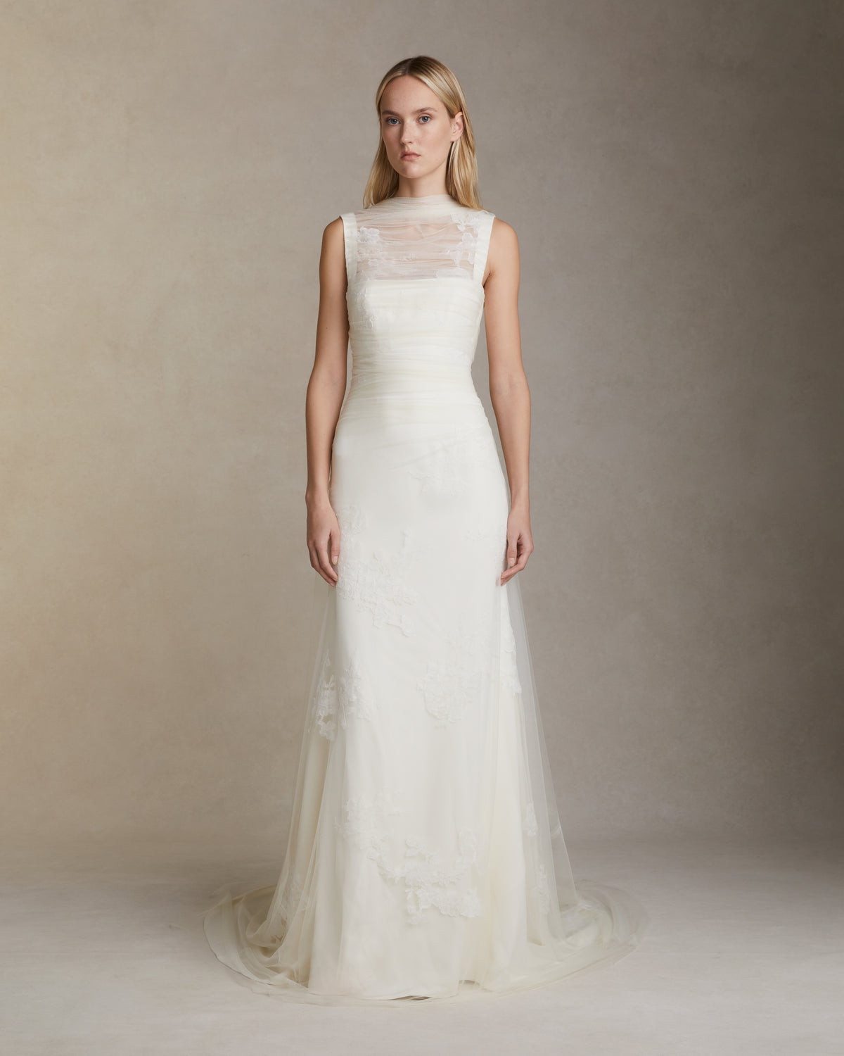 Stretch cady gown with draped soft tulle overlay decorated in hand cut corded and chantilly lace applique. Elongated soft tulle pleated panels drape across bodice and tie at back. Invisible zip closure at center back.