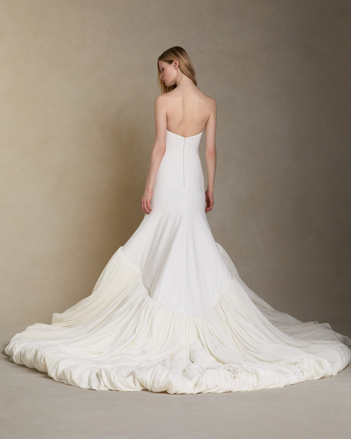 Fluid jersey strapless gown with an elongated seamless fitted bodice. Asymmetric skirt line with a bubbled hem and train. Invisible zip closure at center back.