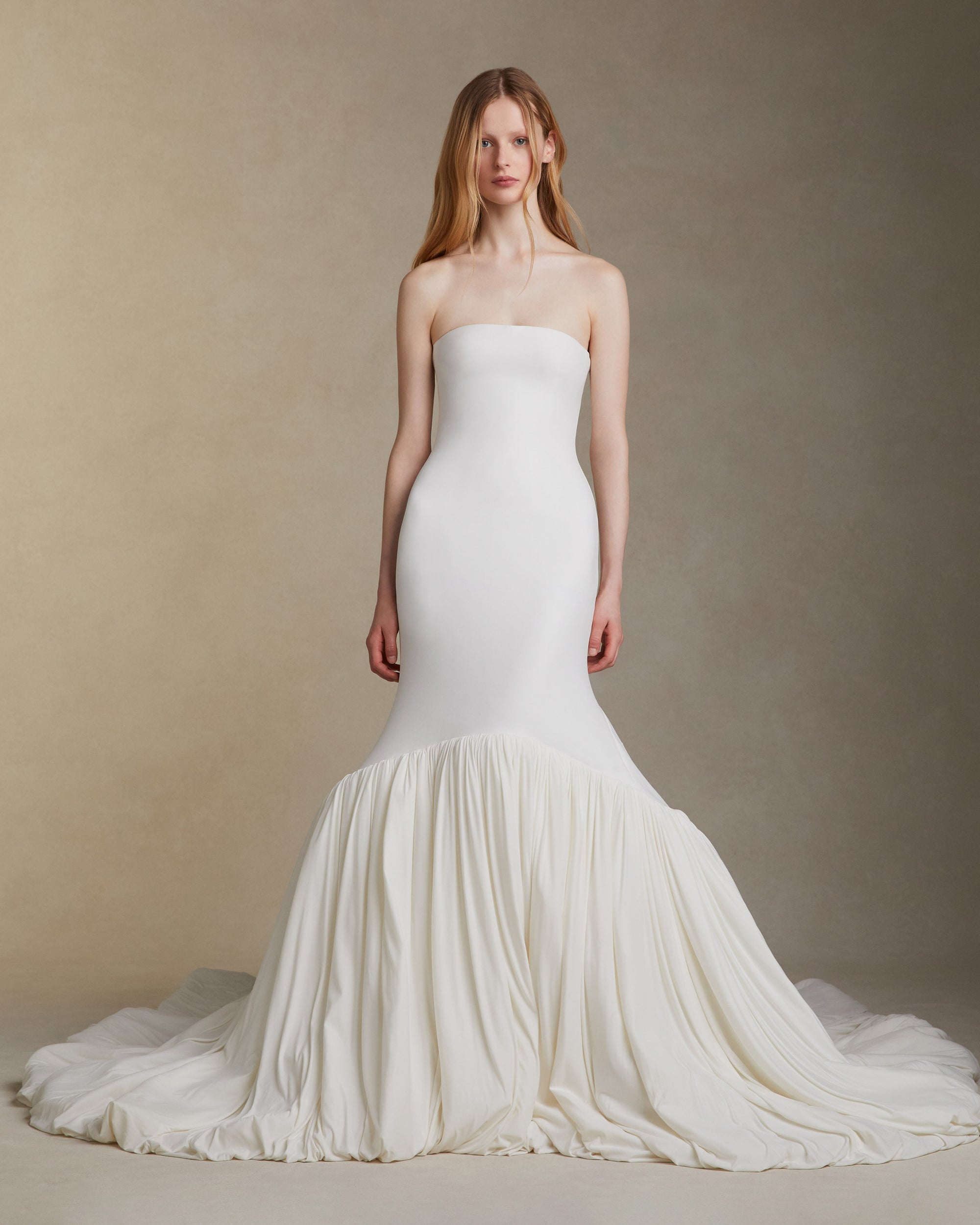 Fluid jersey strapless gown with an elongated seamless fitted bodice. Asymmetric skirt line with a bubbled hem and train. Invisible zip closure at center back.