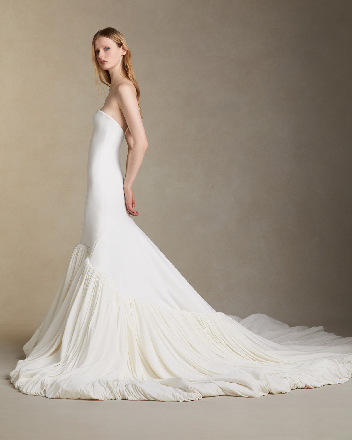 Fluid jersey strapless gown with an elongated seamless fitted bodice. Asymmetric skirt line with a bubbled hem and train. Invisible zip closure at center back.