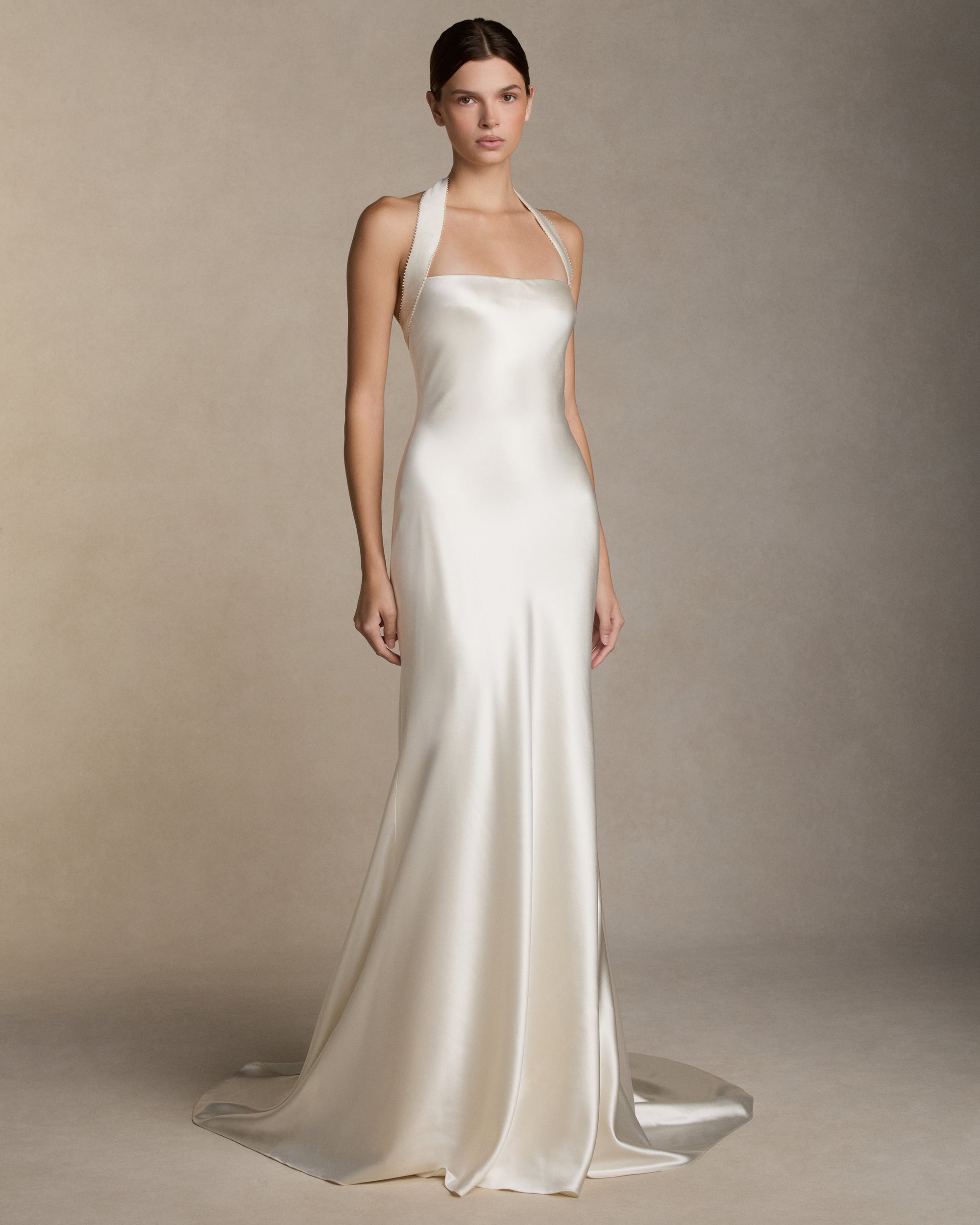 Silk wool bias cut gown with silk wool twill halter strap and micro pearl embroidered trim detail. Invisible zip closure at center back.