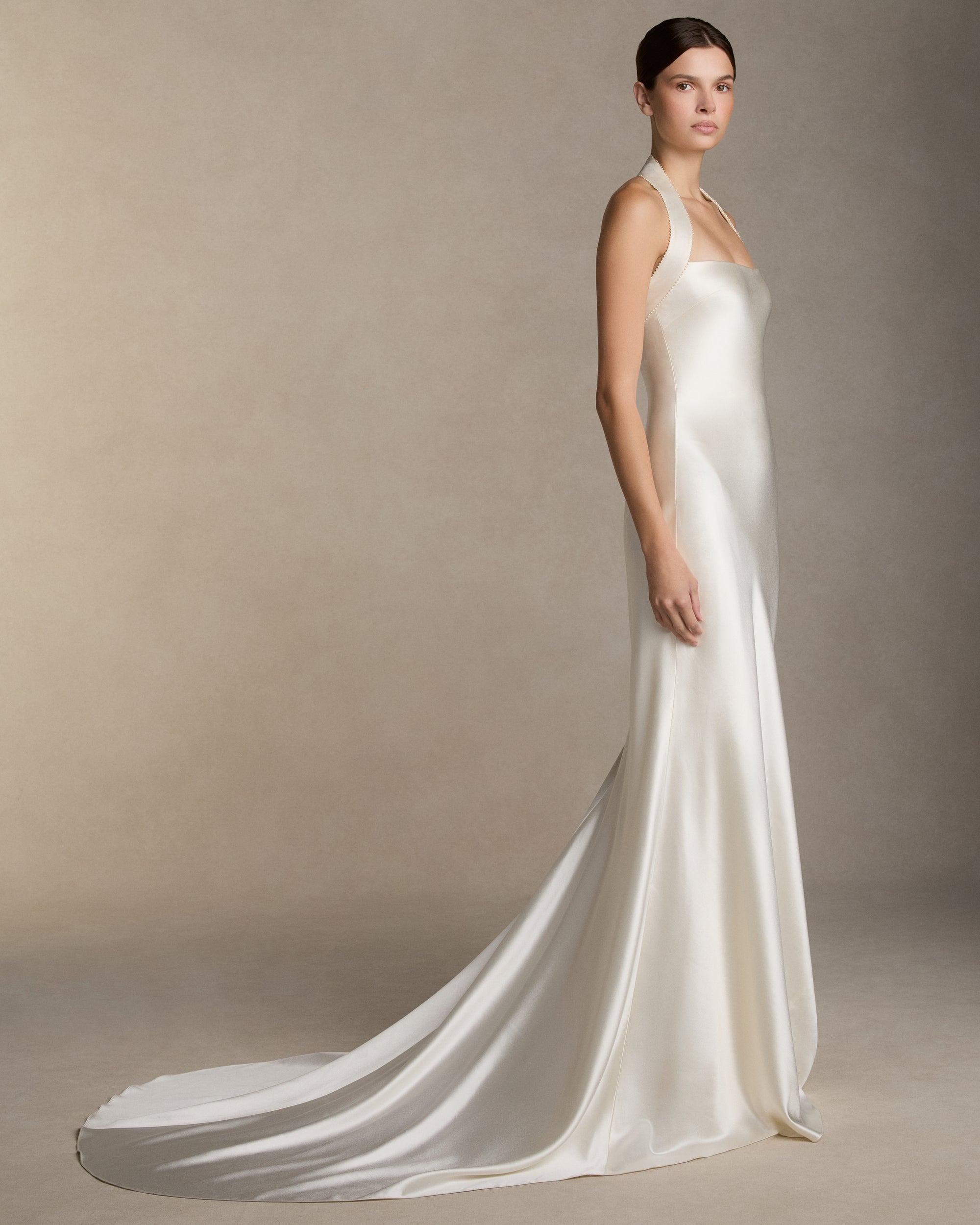 Silk wool bias cut gown with silk wool twill halter strap and micro pearl embroidered trim detail. Invisible zip closure at center back.