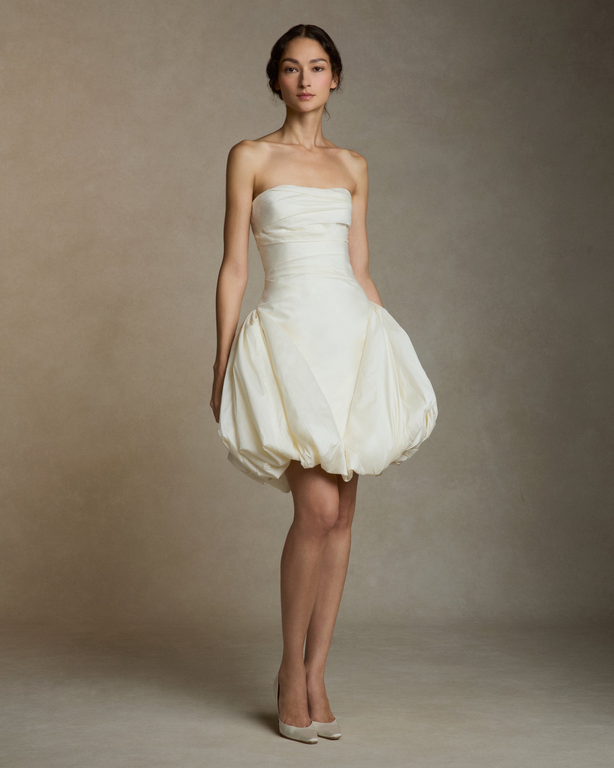 Featherweight silk taffeta draped strapless mini dress with elongated v waistline. Bubble hem skirt releases from the high hip and peels away from the center front. Invisible zip closure at center back.