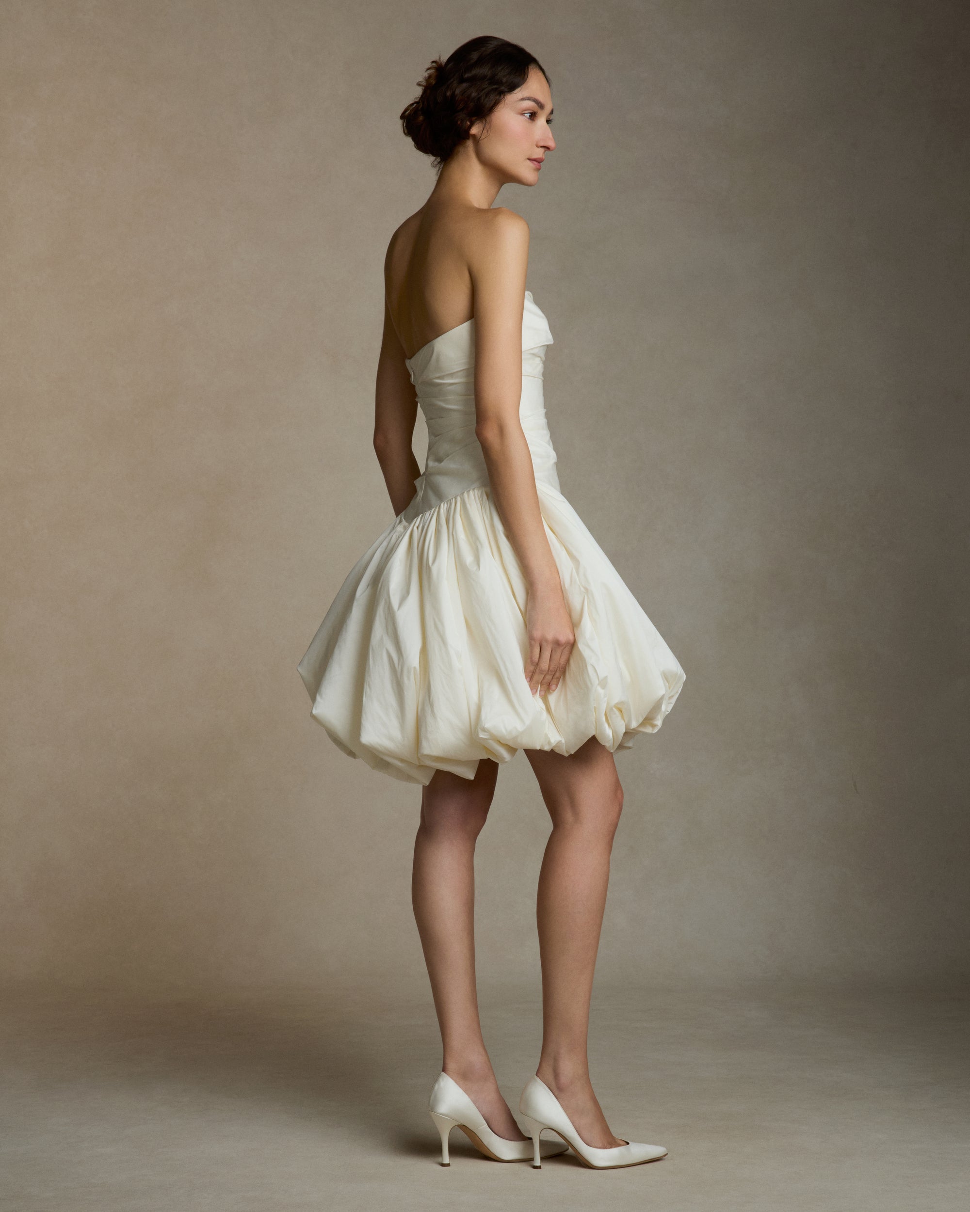 Featherweight silk taffeta draped strapless mini dress with elongated v waistline. Bubble hem skirt releases from the high hip and peels away from the center front. Invisible zip closure at center back.