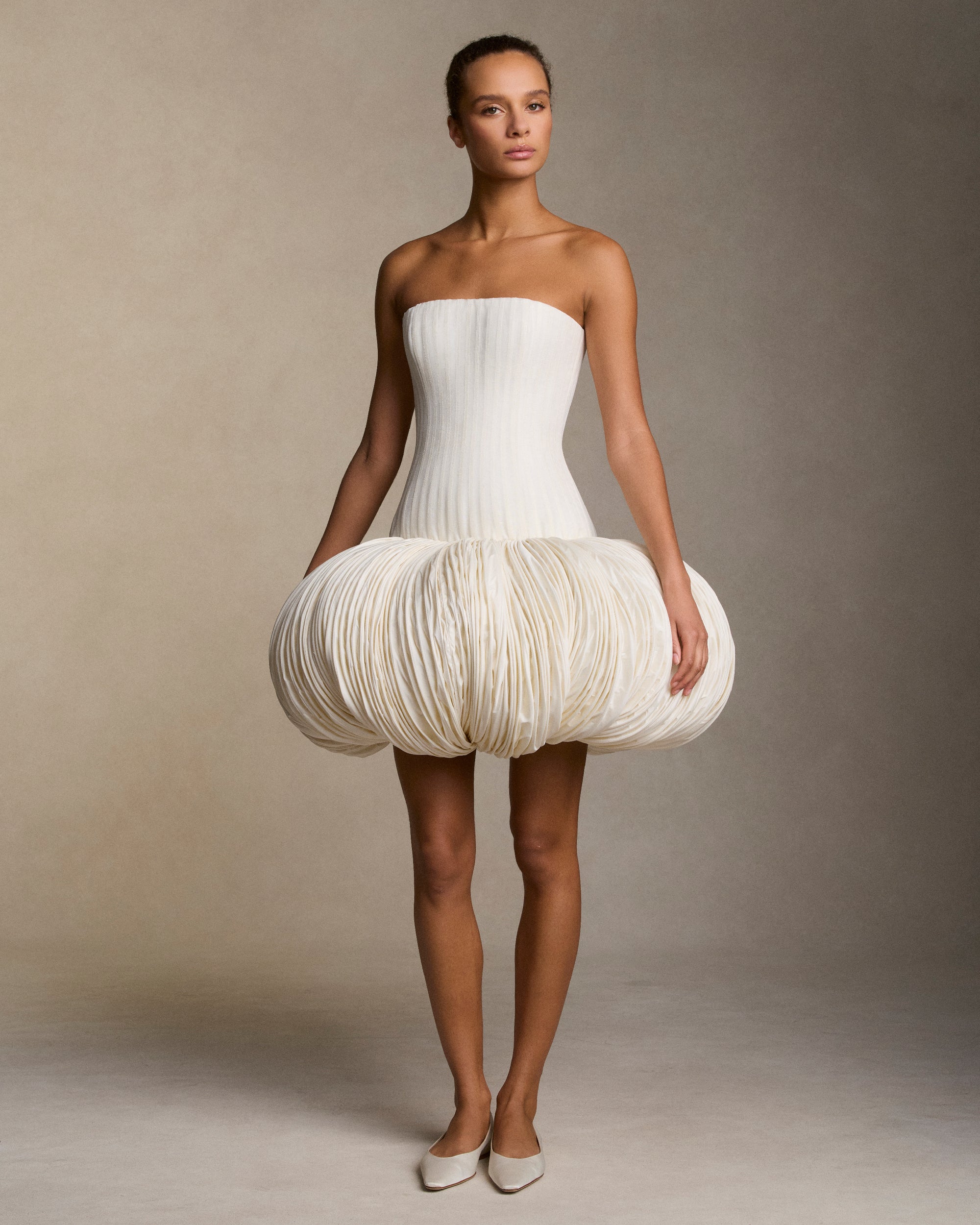 Strapless silk linen organza and tissue taffeta mini dress. Grosgrain boning detail throughout the linen organza bodice frames the silhouette. Exaggerated tissue taffeta bubble skirt is shaped with hundreds of rows of sculptural micro boning. Boned internal bustier, internal grosgrain belt and invisible zip closure at center back.