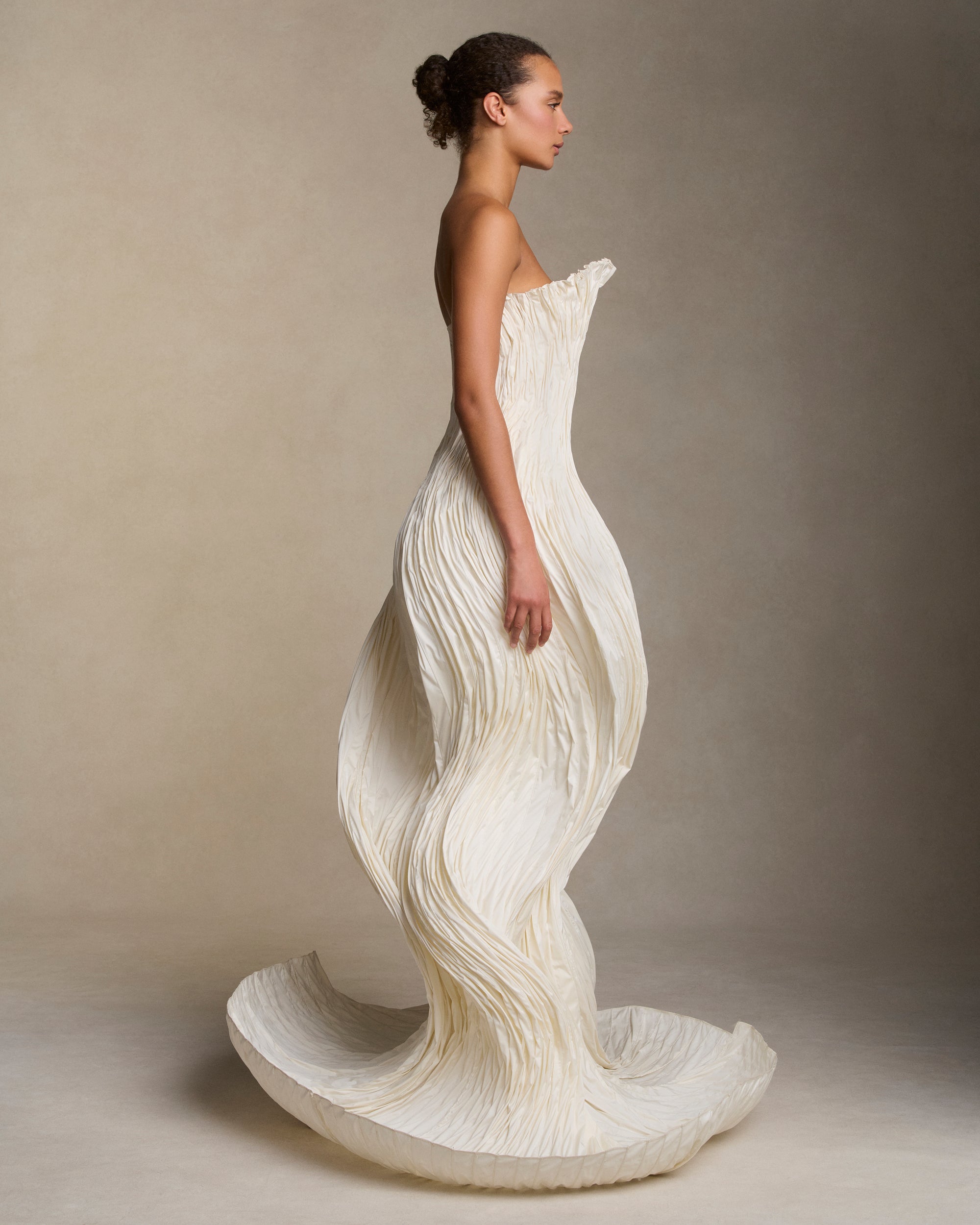 Strapless tissue taffeta ballgown with flared neckline and sculptural shaping created with hundreds of rows of micro boning that twist and curve around the body. Boned internal bustier, internal grosgrain belt and invisible zip closure at center back.