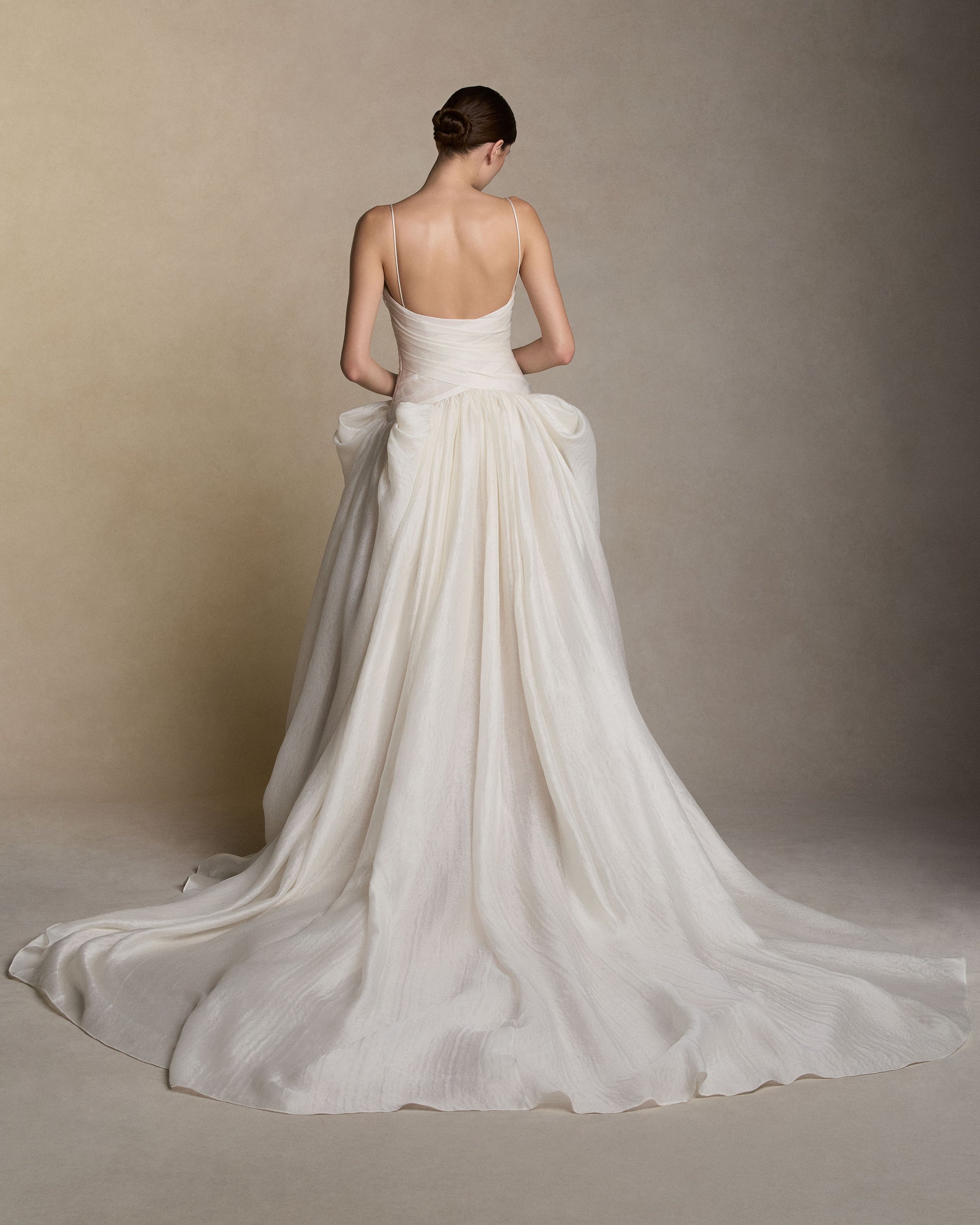 Silk wool gauze spaghetti strap V-neck ball gown with a cross-draped bodice. Peaked draping at the hips releases into a full ball skirt. Boned internal bustier with internal grosgrain waistbelt and  invisible zip closure at center back. 