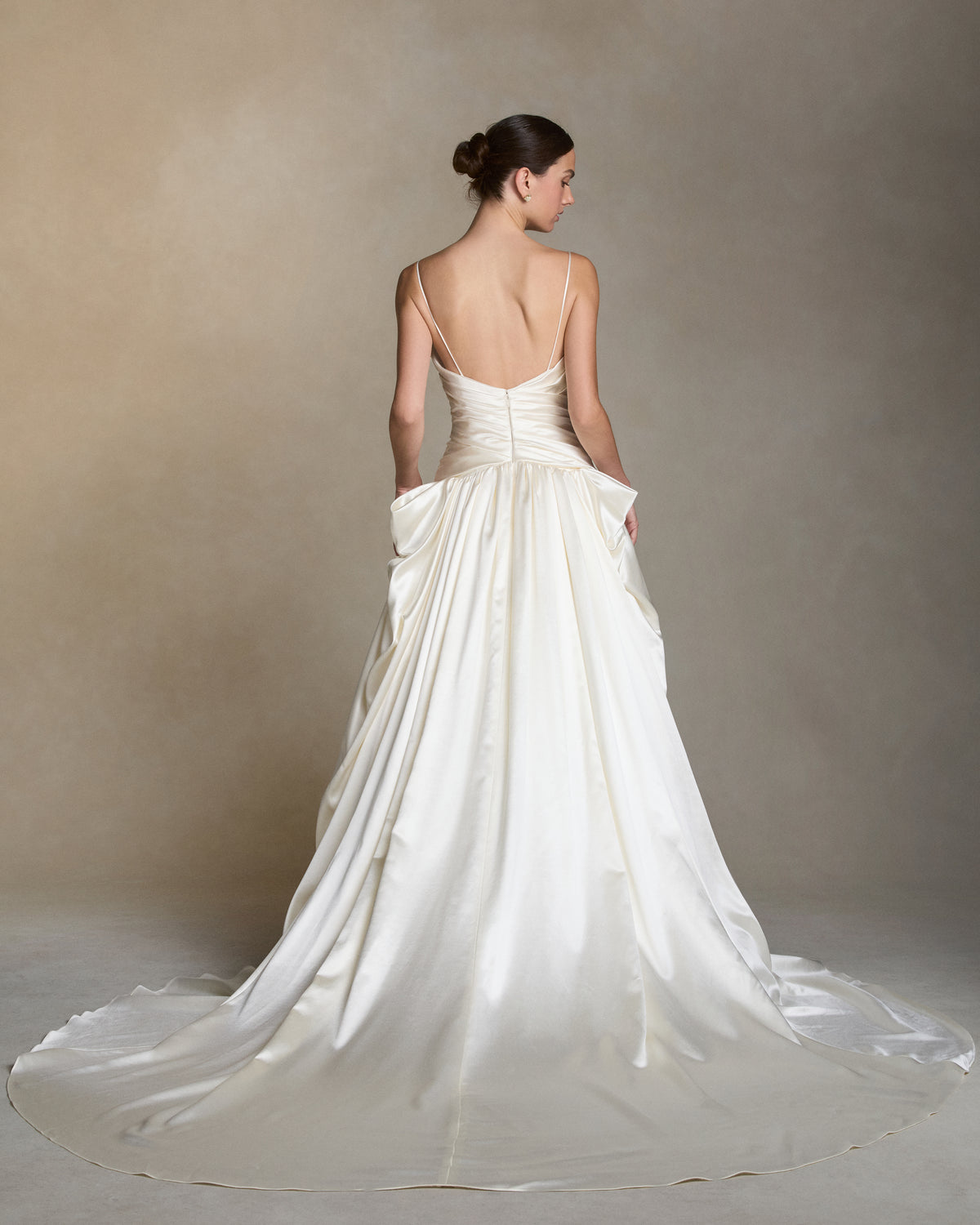 Silk wool spaghetti strap V-neck ball gown with a cross-draped bodice. Peaked draping at the hips releases into a full ball skirt. Boned internal bustier with internal grosgrain waistbelt and  invisible zip closure at center back. 