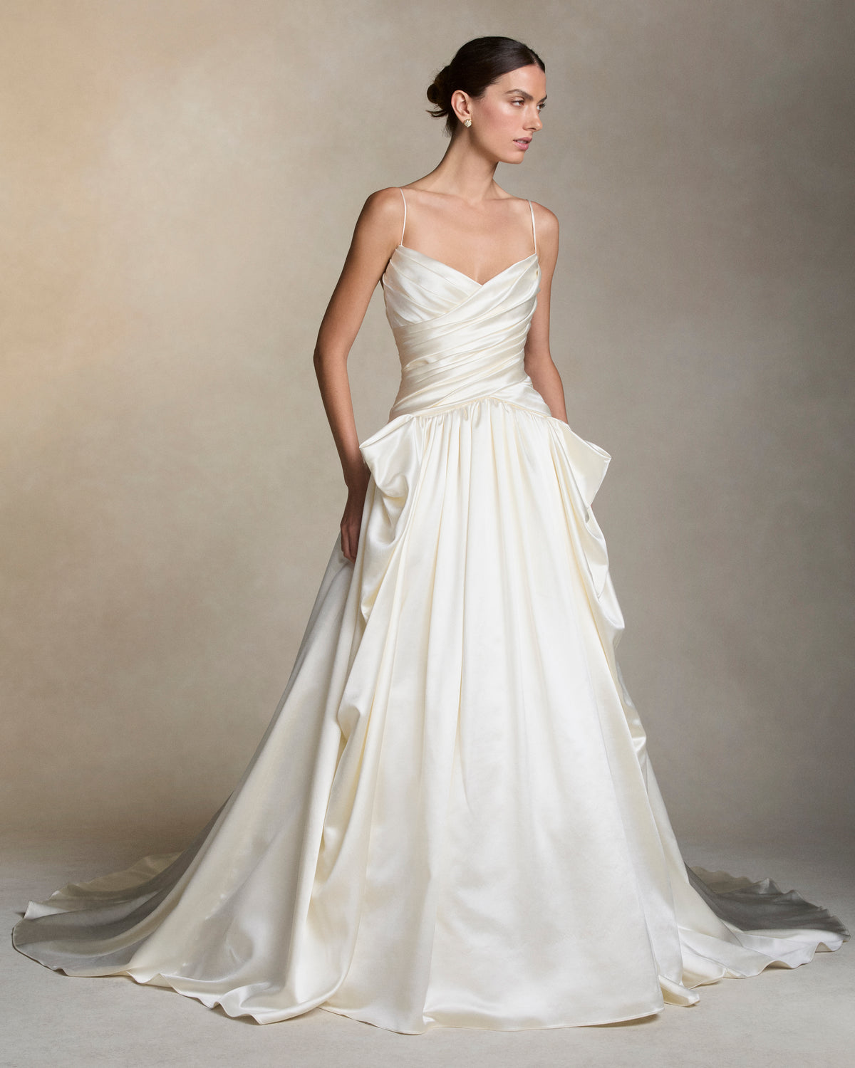 Silk wool spaghetti strap V-neck ball gown with a cross-draped bodice. Peaked draping at the hips releases into a full ball skirt. Boned internal bustier with internal grosgrain waistbelt and  invisible zip closure at center back. 