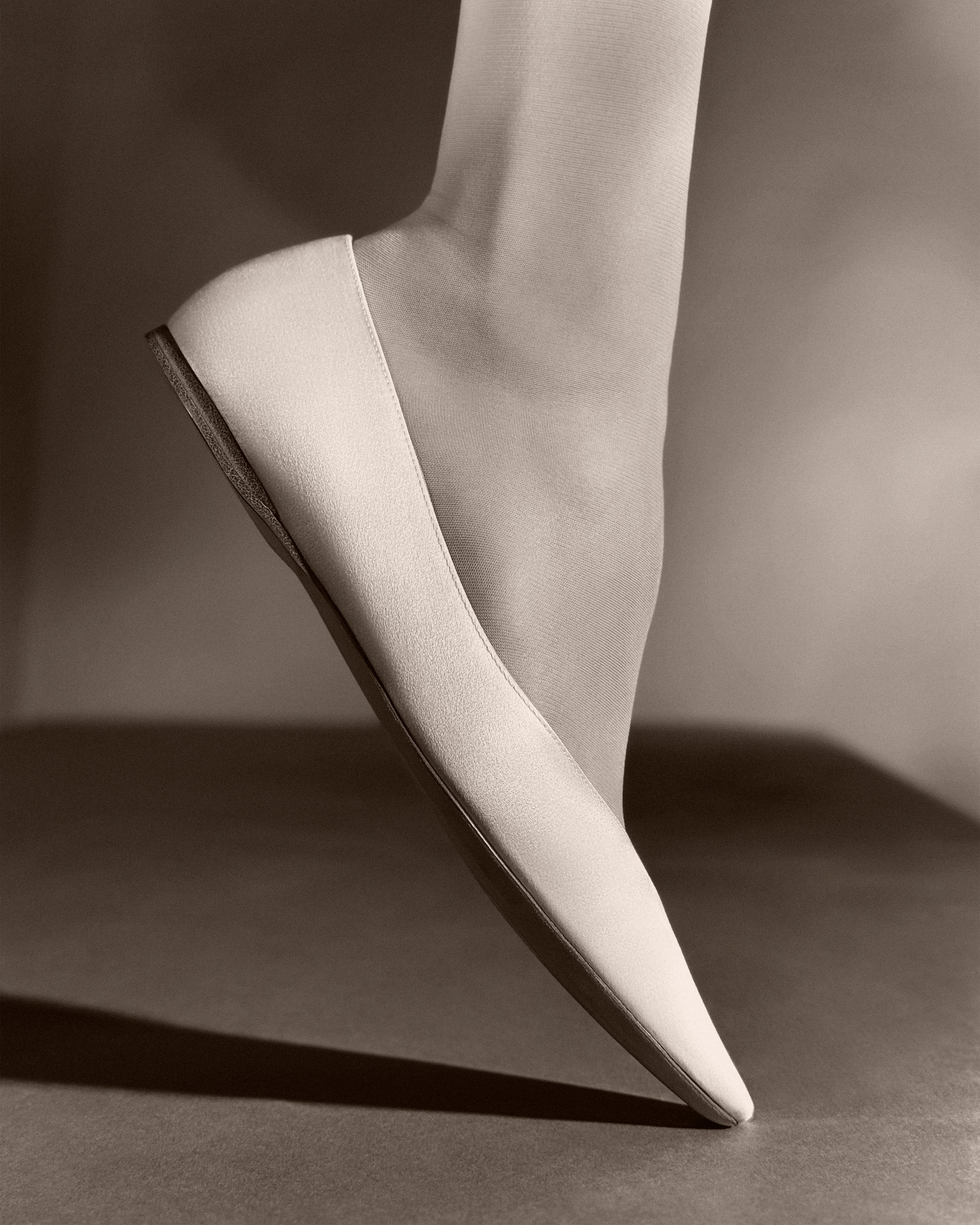 Classic elongated round toe ballerina flat crafted in Italy of ivory satin.