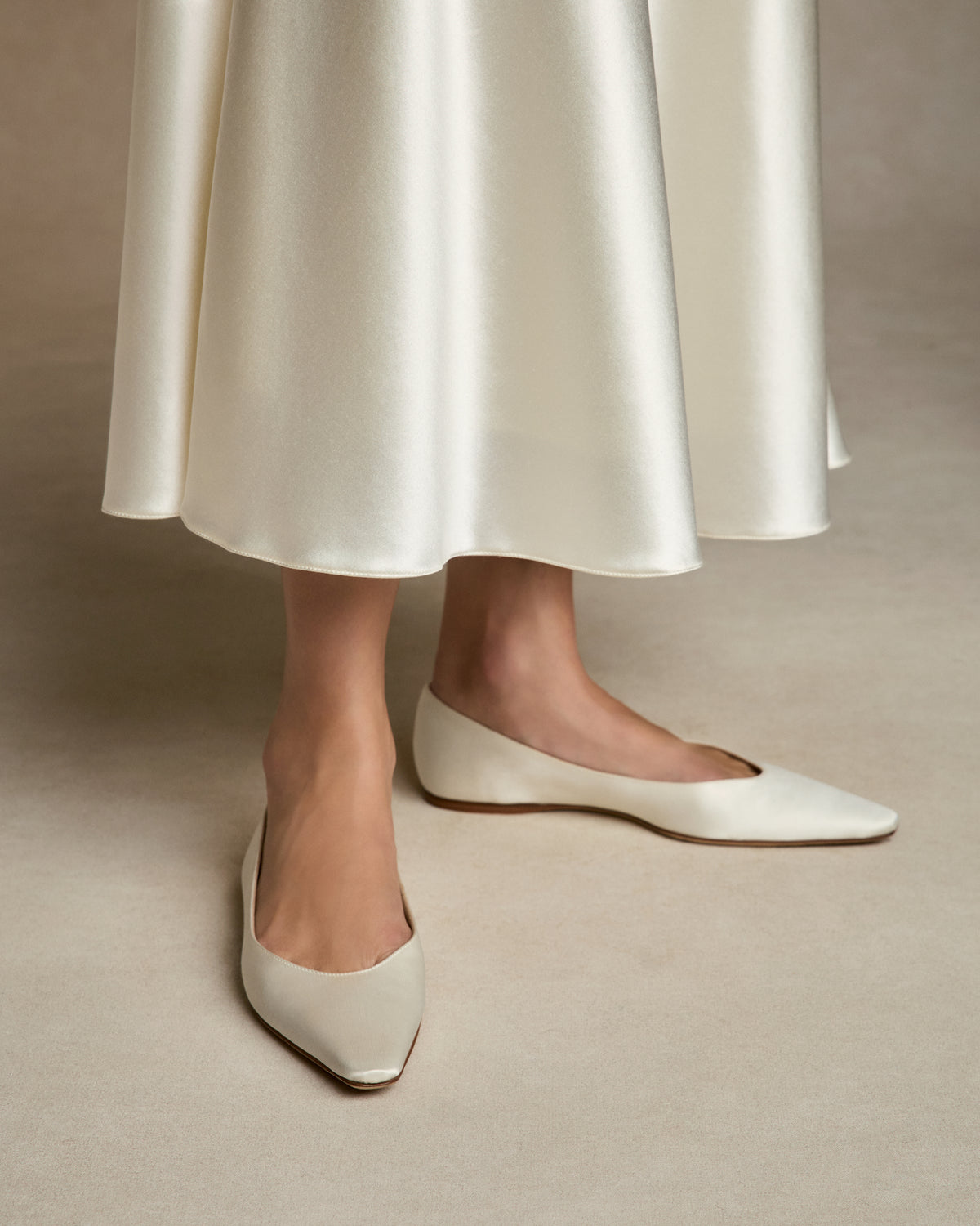 Classic elongated round toe ballerina flat crafted in Italy of ivory satin.