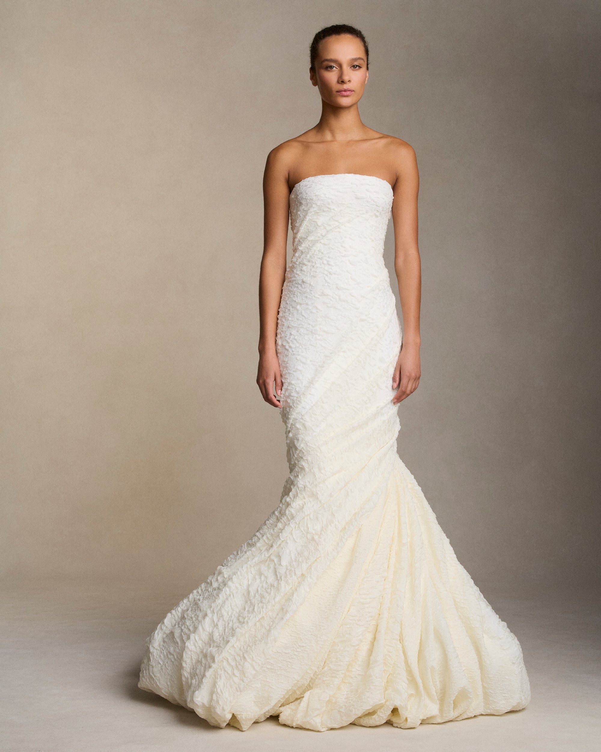 Strapless textured stretch cloqué fluted gown. Twisted drape wraps continuously around the body transcending into a dramatic bubble hem. Boned internal bustier, internal grosgrain belt and invisible zip closure at center back.