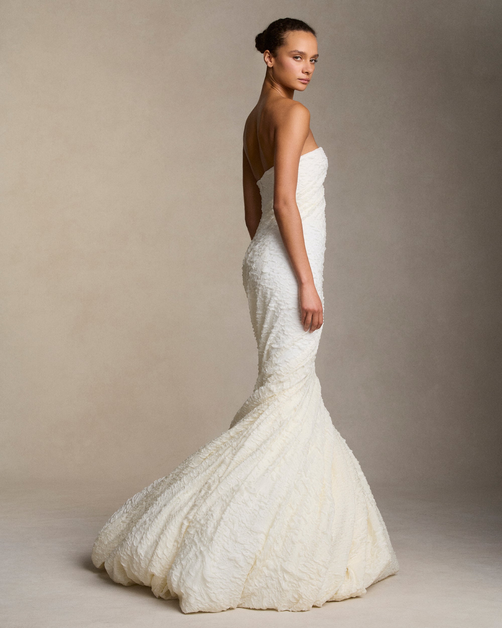 Strapless textured stretch cloqué fluted gown. Twisted drape wraps continuously around the body transcending into a dramatic bubble hem. Boned internal bustier, internal grosgrain belt and invisible zip closure at center back.