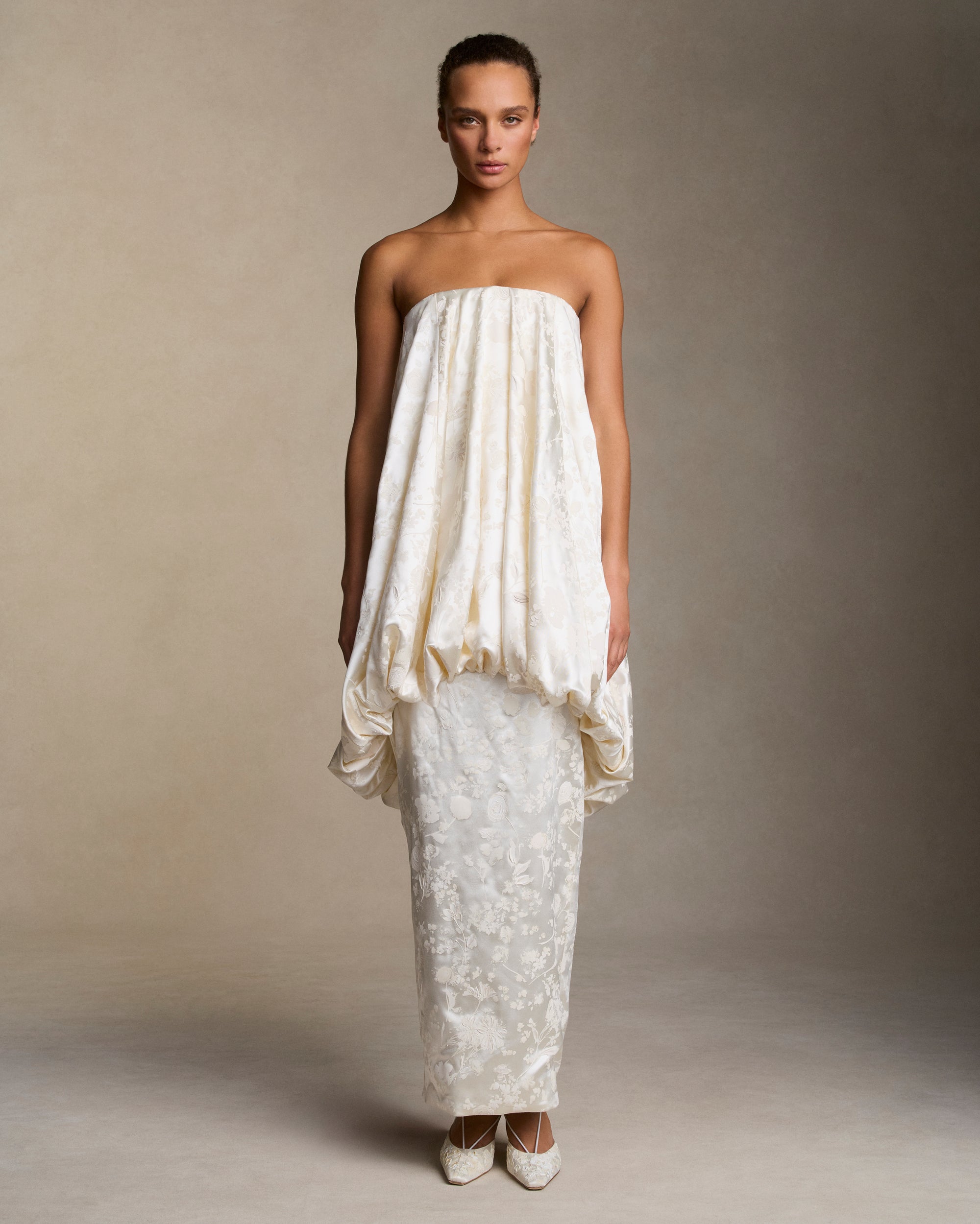 Floral pigment printed and handpainted silk wool strapless column gown. Elongated bubbled bodice overlay falls from neckline ending in a corded channel detail at low hip. Covered button closure down center back, boned internal bustier, internal grosgrain belt and invisible zip closure at center back.