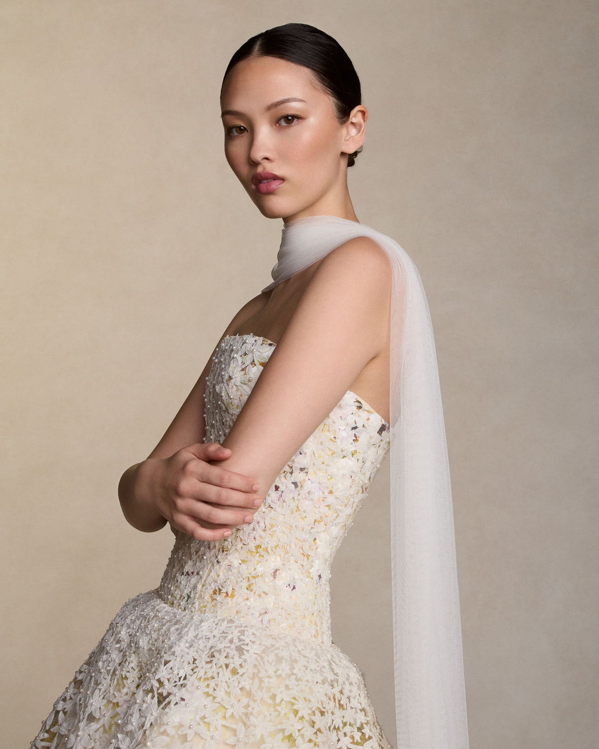 Strapless tea length ball gown with star flower pearl embroidery layered over hand painted silk wool satin. Thousands of hand cut silk chiffon petals with baroque pearls veil a layer of lustrous crinkled metal and silk. Interior lace-up corset with a grosgrain waist belt and double-zip bustier for added structure.