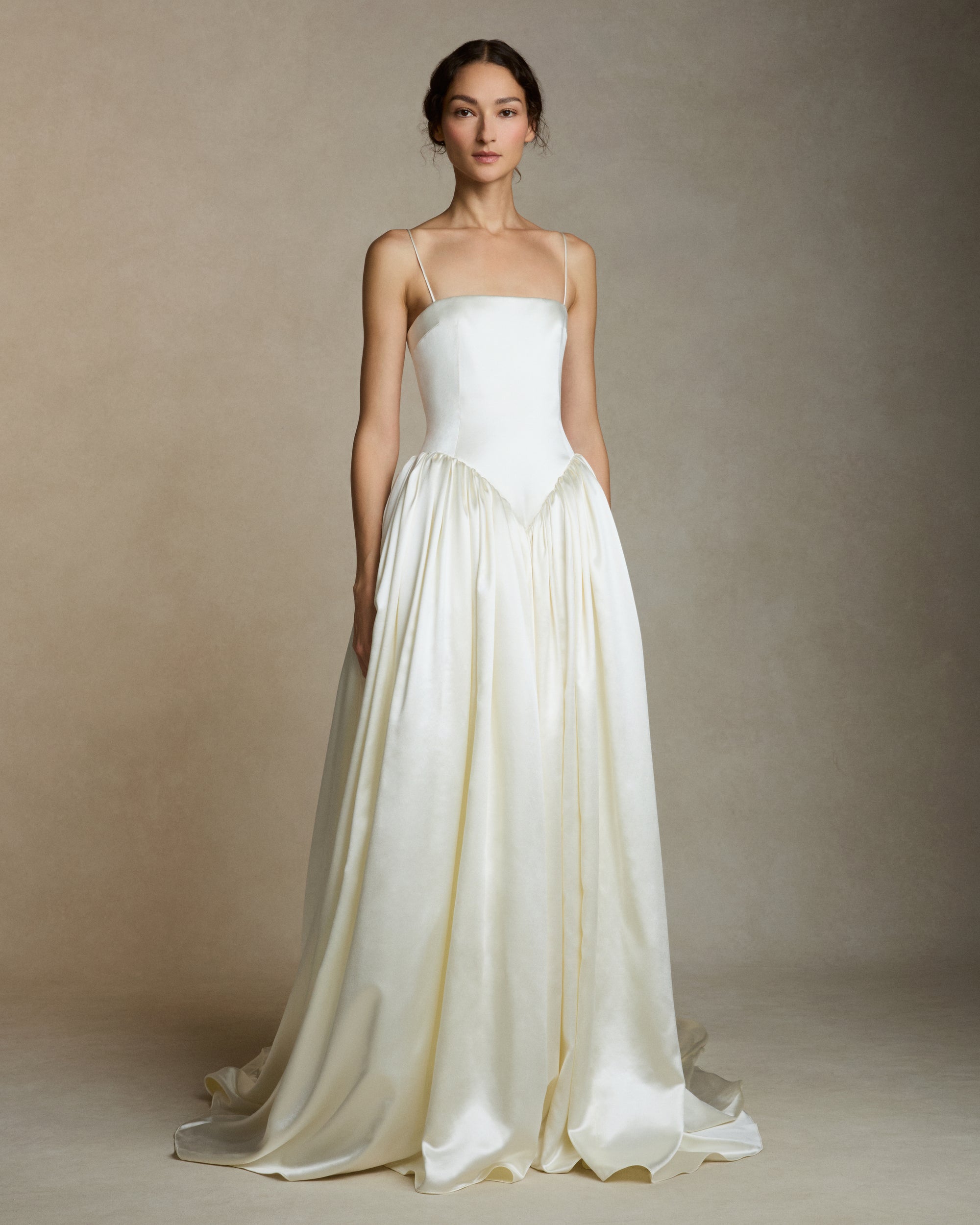 Silk wool straight neck ballgown with dramatic basque waist. Structured sculpted bodice is suspended from delicate spaghetti straps. Gathered waist full ball skirt is finished with baby hem. Boned internal bustier, internal grosgrain belt and invisible zip closure at center back.