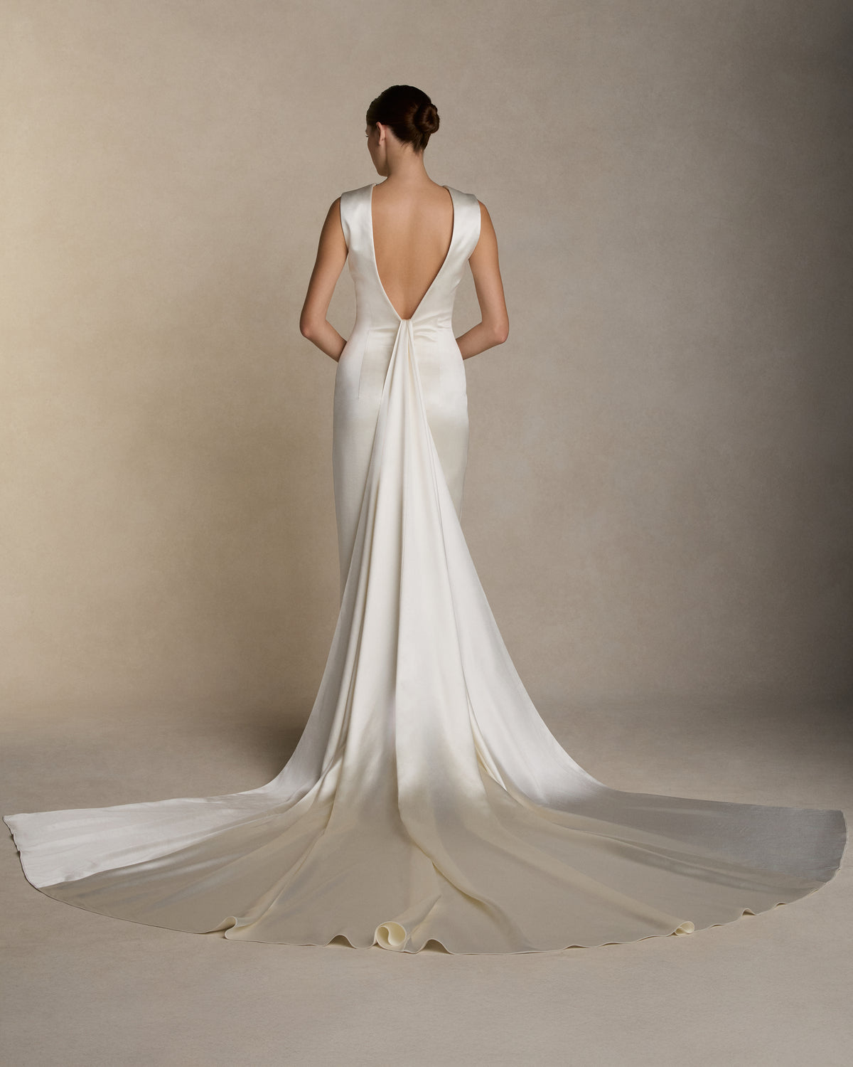 Silk wool column gown with high neckline and deep V back, featuring covered buttons down center back and back slit detail on skirt. Removable watteau train detail is suspended from the back neckline. Invisible zip closure at center back.