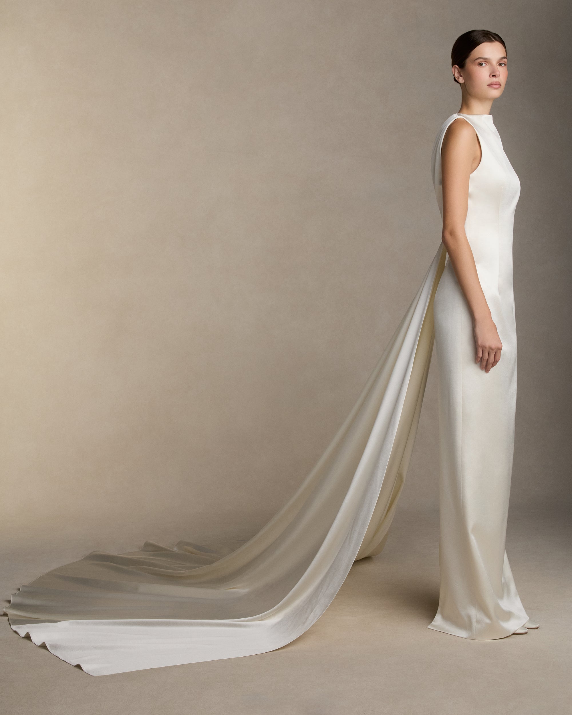 Silk wool column gown with high neckline and deep V back, featuring covered buttons down center back and back slit detail on skirt. Removable watteau train detail is suspended from the back neckline. Invisible zip closure at center back.
