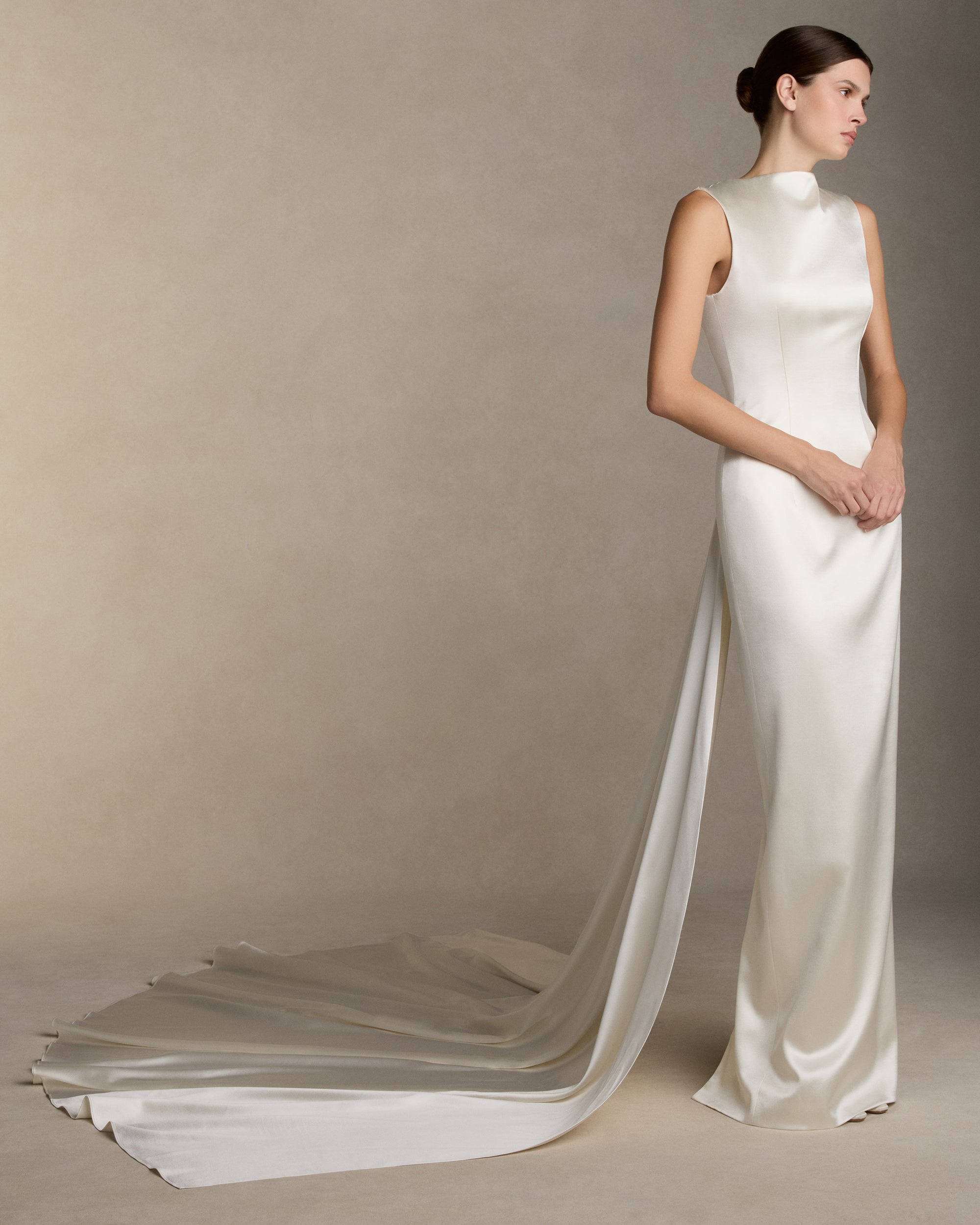 Silk wool column gown with high neckline and deep V back, featuring covered buttons down center back and back slit detail on skirt. Removable watteau train detail is suspended from the back neckline. Invisible zip closure at center back.