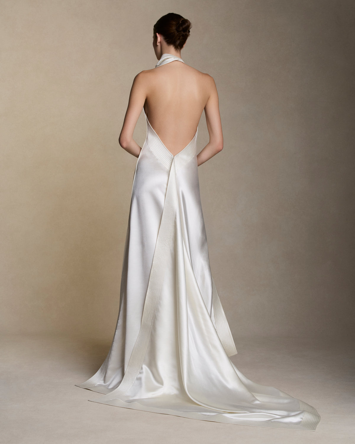 Silk wool handkerchief gown with trapunto stitch border detail. Draped neck cascades asymmetrically down the sideseam falling into an angled train. Button and loop closure at back, invisible zip closure at center back waist.