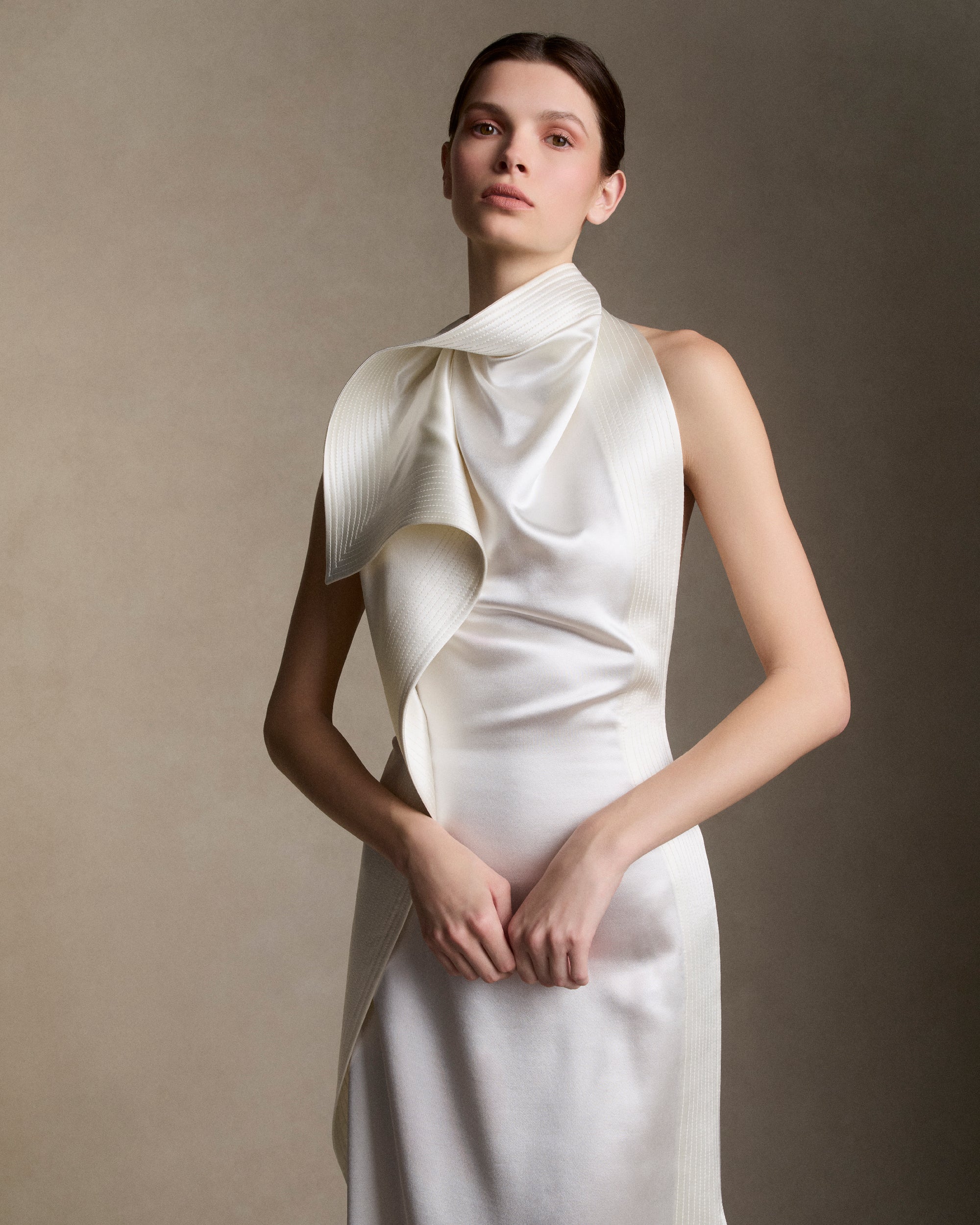 Silk wool handkerchief gown with trapunto stitch border detail. Draped neck cascades asymmetrically down the sideseam falling into an angled train. Button and loop closure at back, invisible zip closure at center back waist.