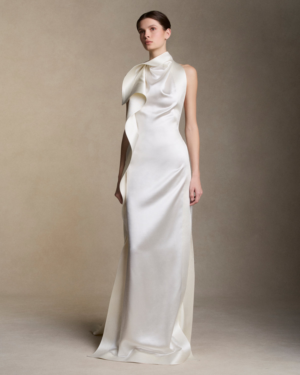 Silk wool handkerchief gown with trapunto stitch border detail. Draped neck cascades asymmetrically down the sideseam falling into an angled train. Button and loop closure at back, invisible zip closure at center back waist.