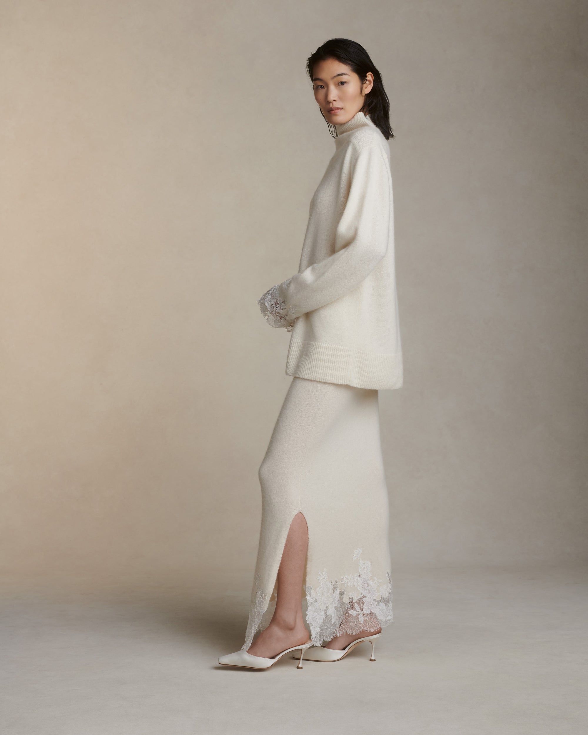 Silk cashmere knit pullover with hand cut chantilly and corded lace applique at sleeve opening. Angled high neck with rib knit sloped shoulder yoke. Side slits at sleeve opening. Rib knit hem.Styled with Viv skirt