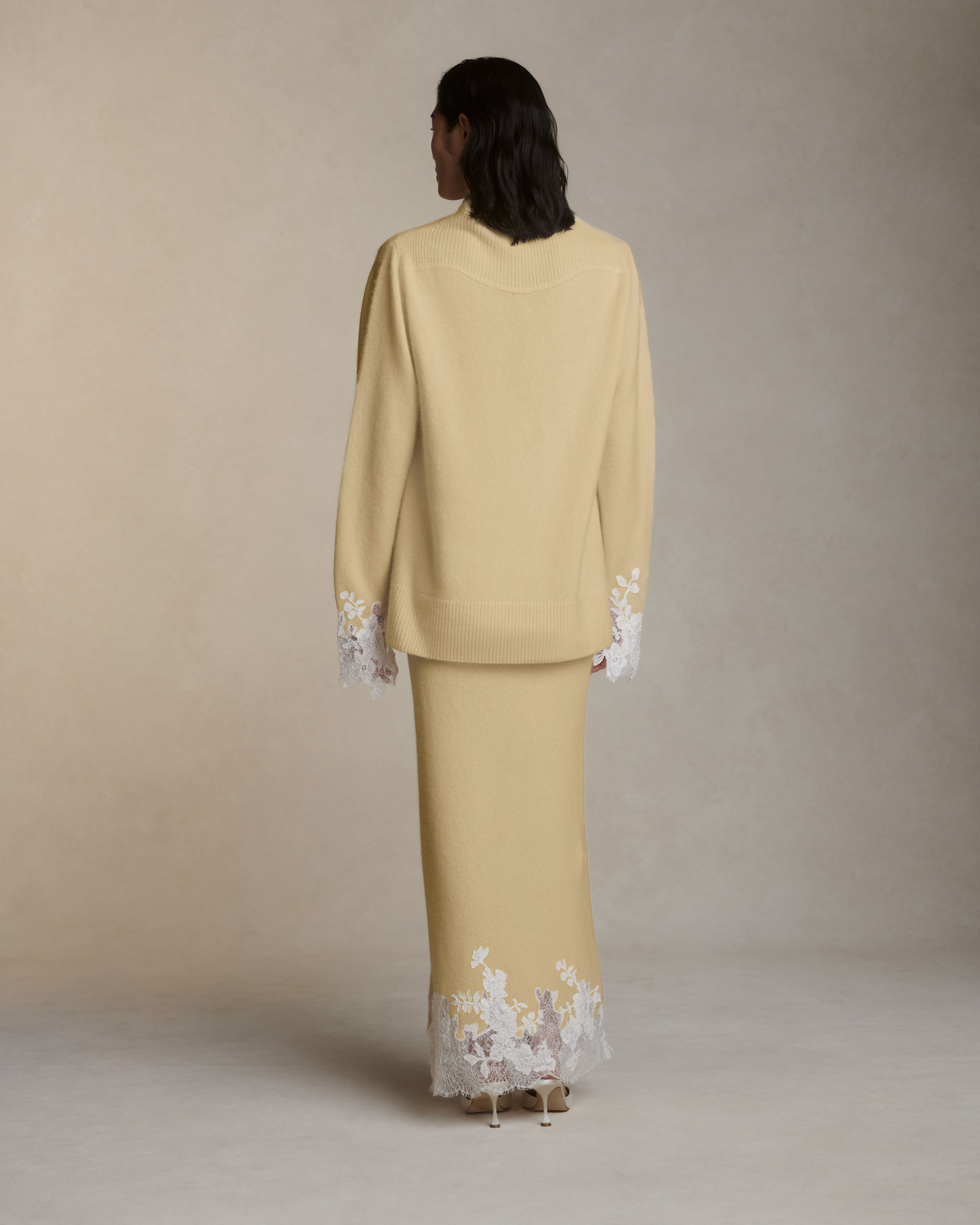 Silk cashmere slip on skirt with hand cut chantilly and corded lace applique adorning hem. Left side slit. Elasticated waist.Styled with Sid pullover
