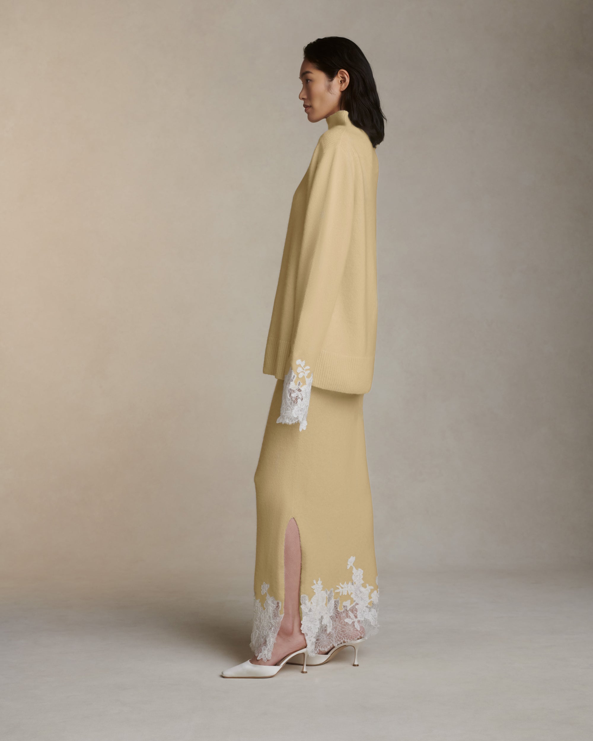 Silk cashmere slip on skirt with hand cut chantilly and corded lace applique adorning hem. Left side slit. Elasticated waist.Styled with Sid pullover