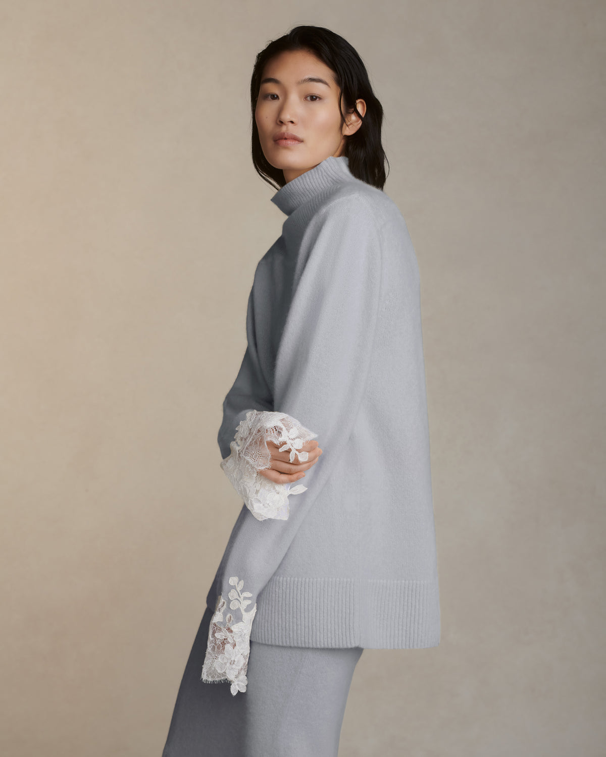 Silk cashmere knit pullover with hand cut chantilly and corded lace applique at sleeve opening. Angled high neck with rib knit sloped shoulder yoke. Side slits at sleeve opening. Rib knit hem.Styled with Viv skirt