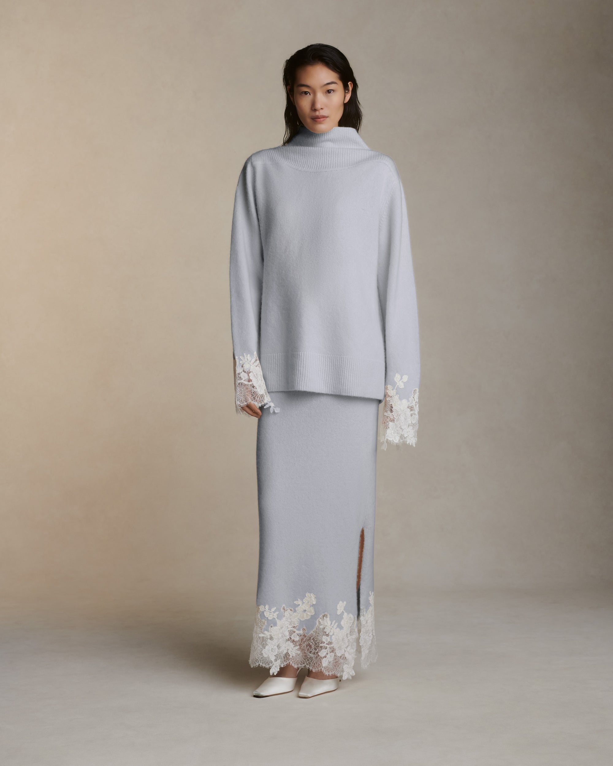 Silk cashmere knit pullover with hand cut chantilly and corded lace applique at sleeve opening. Angled high neck with rib knit sloped shoulder yoke. Side slits at sleeve opening. Rib knit hem.Styled with Viv skirt