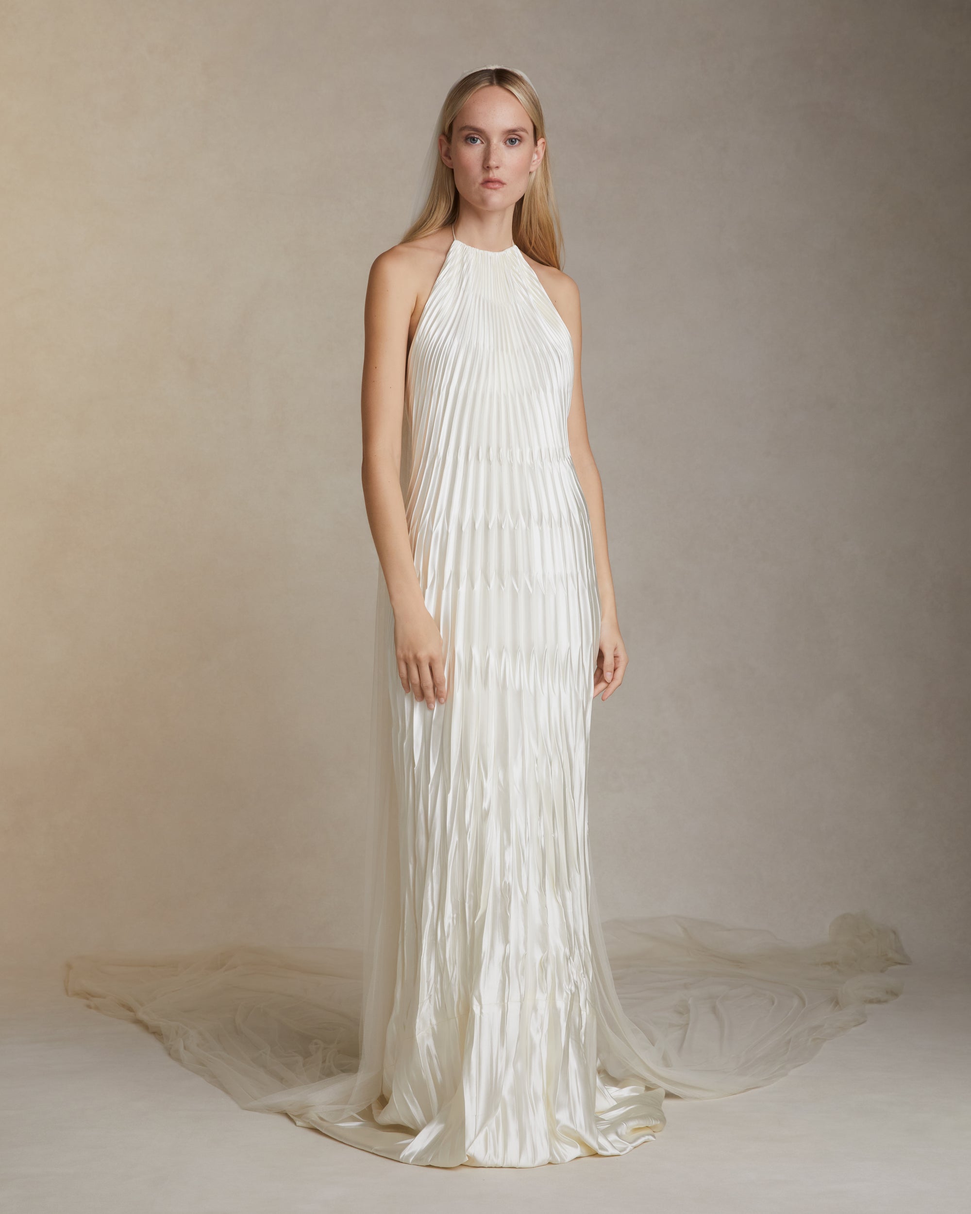 Pleated and hand crinkled silk wool halter neck gown. Spaghetti tie closure with baroque pearl cord end detail. Invisible zip closure at center back.