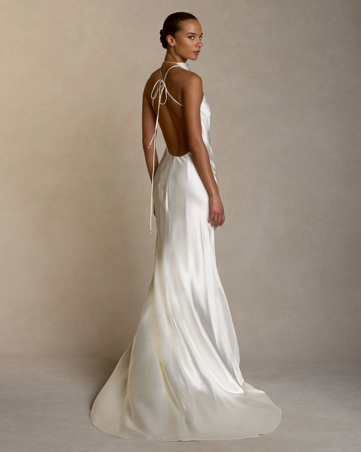 Bias cut silk wool high neck halter gown. Spaghetti tie closure with baroque pearl cord end detail. Invisible zip closure at center back.