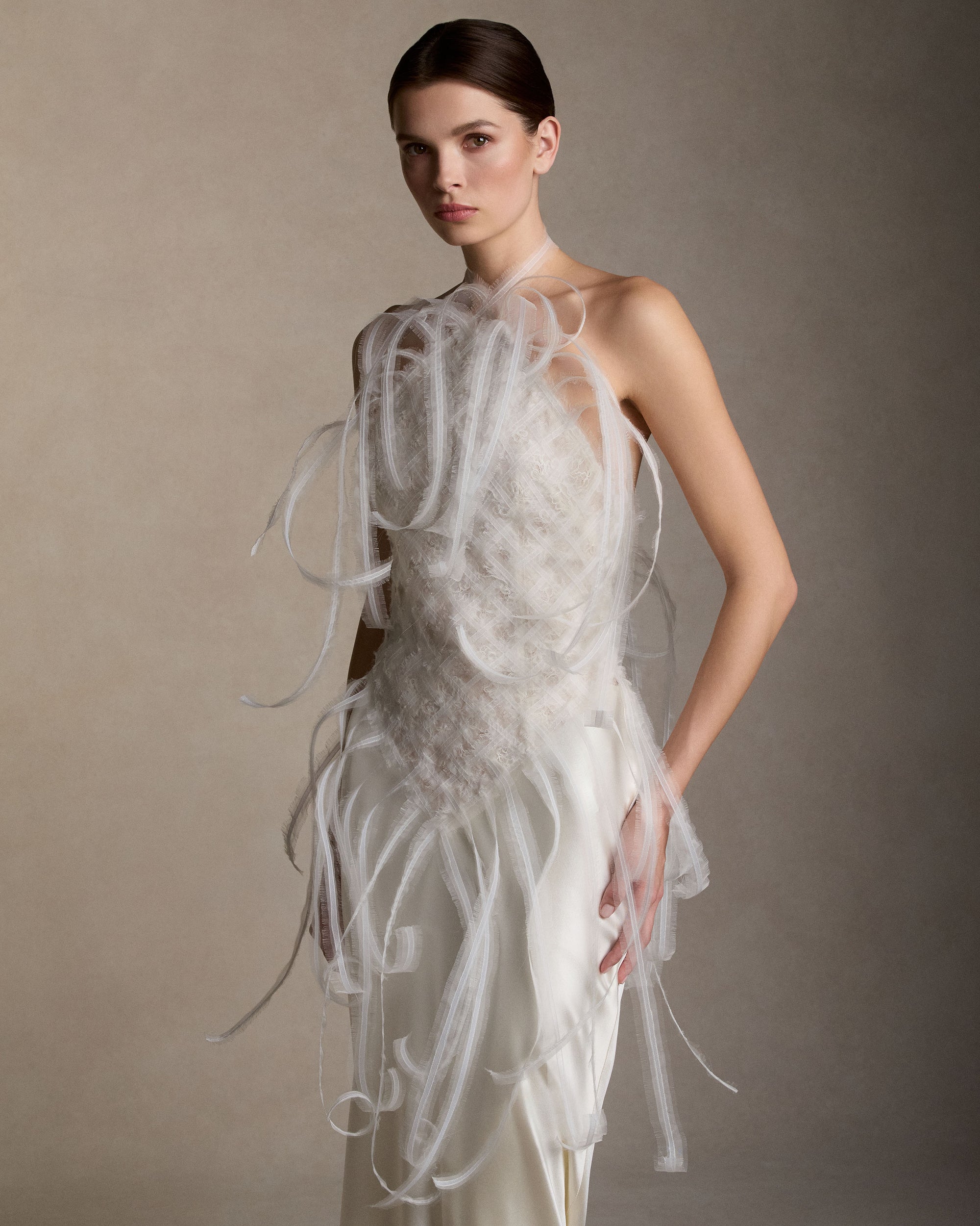 Silk organza embroidered halter top. Frayed silk organza layered over horsehair creates a textural woven fabric, releasing into undulating fringe at the neckline and waistline. Corded lace and silk chiffon are layered beneath to create dimension. Invisible center back zip. Styled with Dree skirt