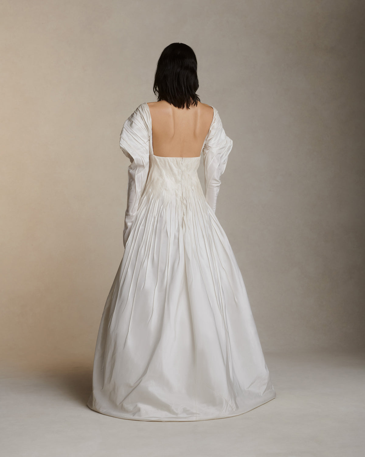 Tucked taffeta off the shoulder ball gown with crinoline encapsulated bubble hem. Boning and gummy tape at neckline for structure and security leading into draped, full length sleeves. Soft internal corset with wireless cups, grosgrain waistband with 3 position closure for support and external center back zipper. Organza and can can lined skirt for volume and hold. Available hand-dyed as editorial version $14990