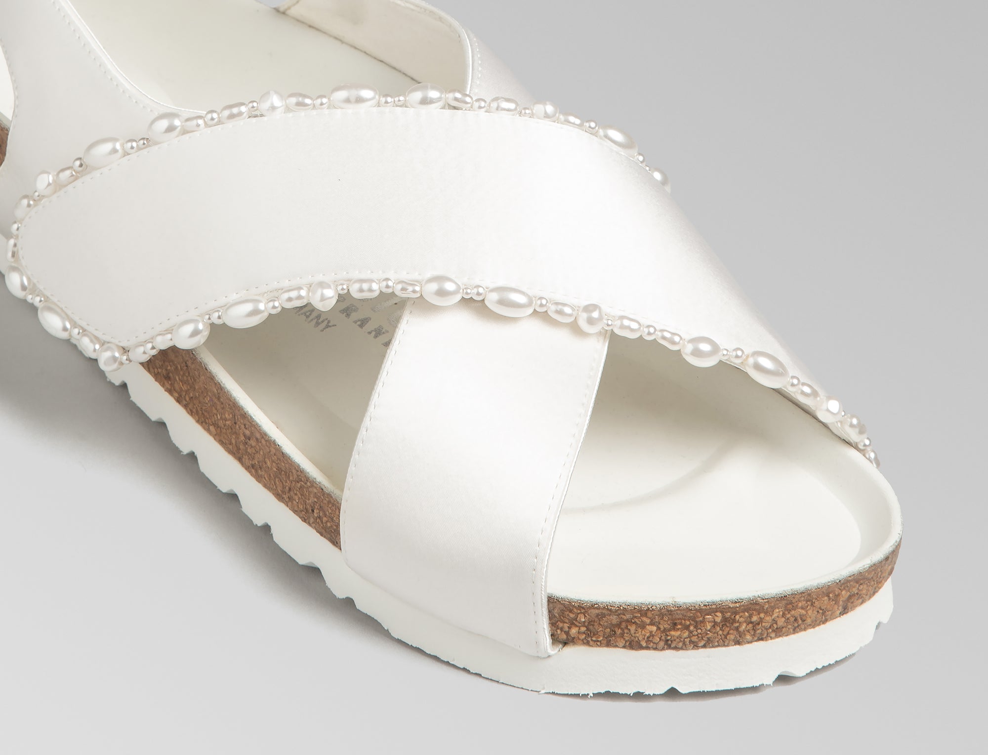 The Tulum is reimagined in a luminous ivory satin, featuring a graceful crossover profile and a slim ankle strap adorned with delicate pearls. The design also introduces an innovative adjustable hidden buckle closure. Handcrafted in Germany, the shoe merges BIRKENSTOCK’s legendary comfort with Danielle Frankel’s signature touch of refined elegance.- Upper: Delicate satin upper, naturally shaped pearls handstitched on trim- Footbed: Anatomical shaped BIRKENSTOCK cork latex Footbed lined with premium Nappa Leather- Sole: EVA die cut outsole with a custom design, blending classic BIRKENSTOCK bone pattern with delicate leaf inspired detailing