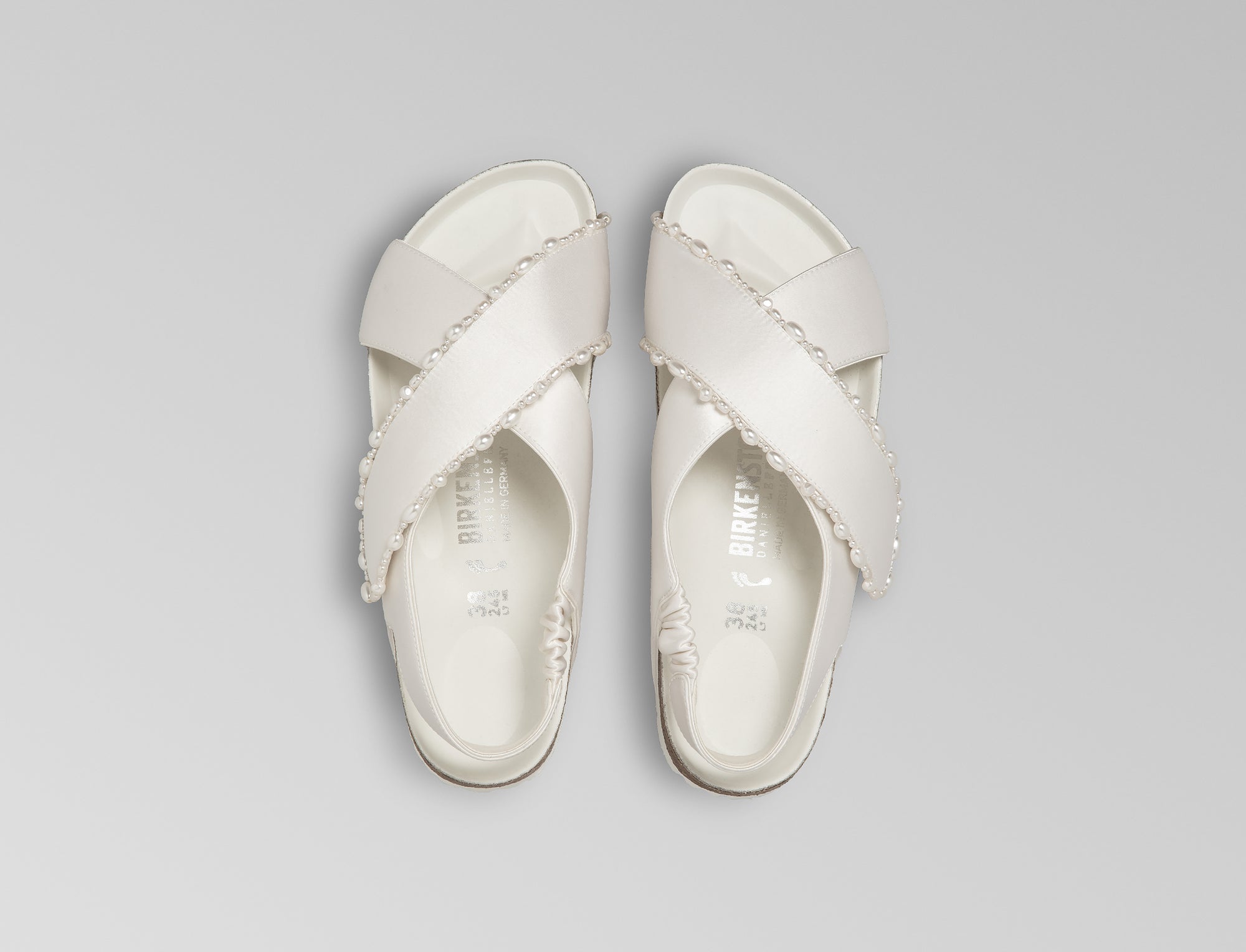 The Tulum is reimagined in a luminous ivory satin, featuring a graceful crossover profile and a slim ankle strap adorned with delicate pearls. The design also introduces an innovative adjustable hidden buckle closure. Handcrafted in Germany, the shoe merges BIRKENSTOCK’s legendary comfort with Danielle Frankel’s signature touch of refined elegance.- Upper: Delicate satin upper, naturally shaped pearls handstitched on trim- Footbed: Anatomical shaped BIRKENSTOCK cork latex Footbed lined with premium Nappa Leather- Sole: EVA die cut outsole with a custom design, blending classic BIRKENSTOCK bone pattern with delicate leaf inspired detailing