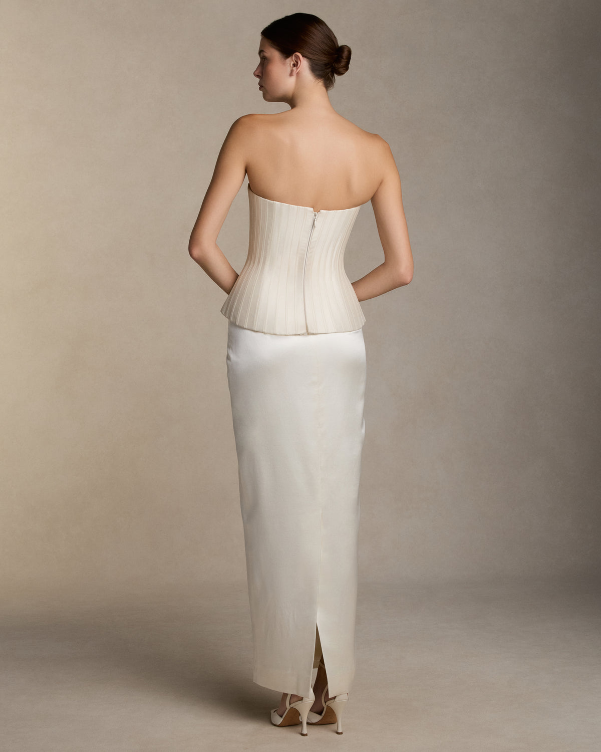 Structured silk wool twill strapless bustier with sharp waistline. Grosgrain boning detail throughout the bodice frames the silhouette. Boned internal bustier, internal grosgrain belt and invisible zip closure at center back.Styled with Tristan skirt