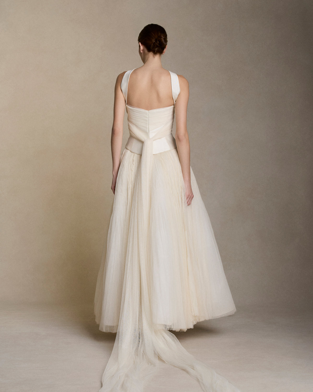 Silk wool twill bustier with curved shaped seams and attached neck wrap detail. Gathered and draped soft tulle frames the bust wrapping the body descending into tulle streamers at center back. Boned internal bustier, internal grosgrain belt and invisible zip closure at center back.Styled with Georgia Skirt