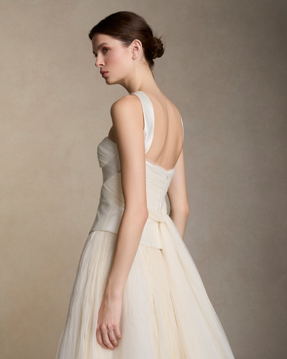 Silk wool twill bustier with curved shaped seams and attached neck wrap detail. Gathered and draped soft tulle frames the bust wrapping the body descending into tulle streamers at center back. Boned internal bustier, internal grosgrain belt and invisible zip closure at center back.Styled with Georgia Skirt