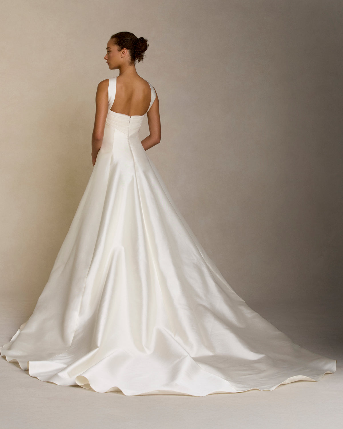 Silk wool twill ballgown with curved shaped seams and attached neck wrap detail. Gathered and draped tulle frames the bust wrapping towards the center back. Boned internal bustier, internal grosgrain belt and invisible zip closure at center back.