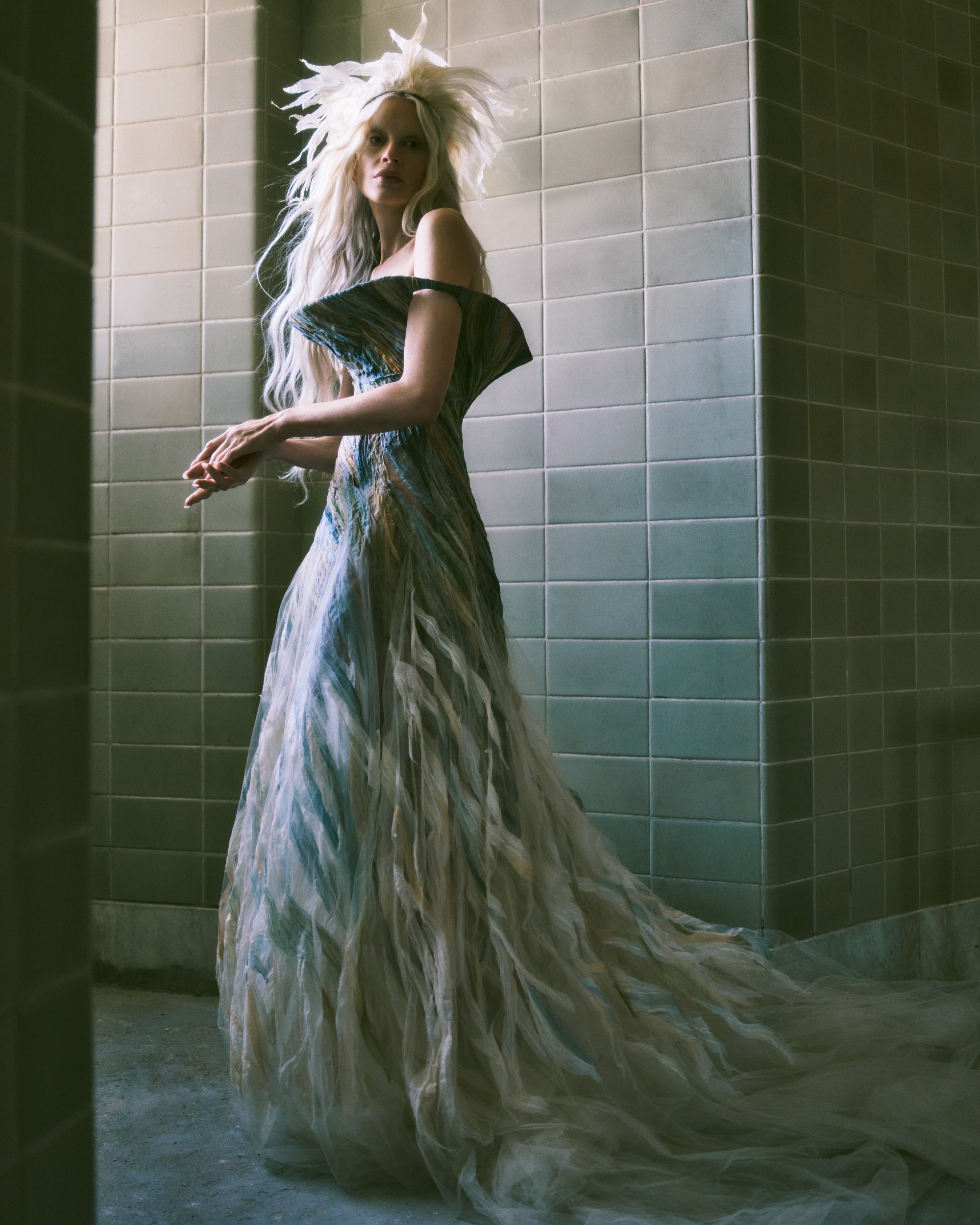 Strapless illusion tulle gown with sculptural flared neckline. Hand dyed hand cut silk chiffon watercolor strips ripple around the body, cascading into a bubble hem. Boned internal bustier, internal grosgrain belt and invisible zip closure at center back.