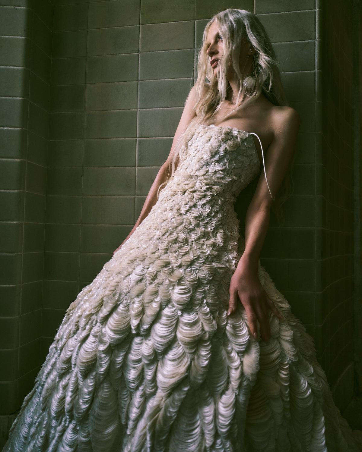 Dipped neckline spaghetti strap ballgown decorated entirely with hand cut silk wool cascading petal embroidery. Thousands of hand applied silk wool petals undulate with texture throughout the gown falling into a dramatic bubble hem. Boned internal bustier, internal grosgrain belt and invisible zip closure at center back.