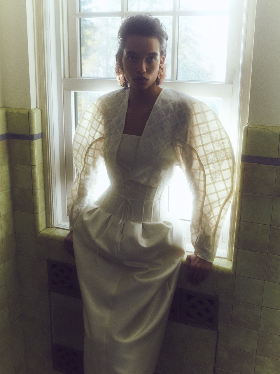 Sculptural linen organza cropped jacket framed with silk organza and grosgrain ribbon trellis detail. Hand cut and chantilly lace appliqued throughout. Satin piping detail and long grosgrain ribbon tie detail at center front. Covered button and loop closure at sleeve opening.Styled with Audra gown