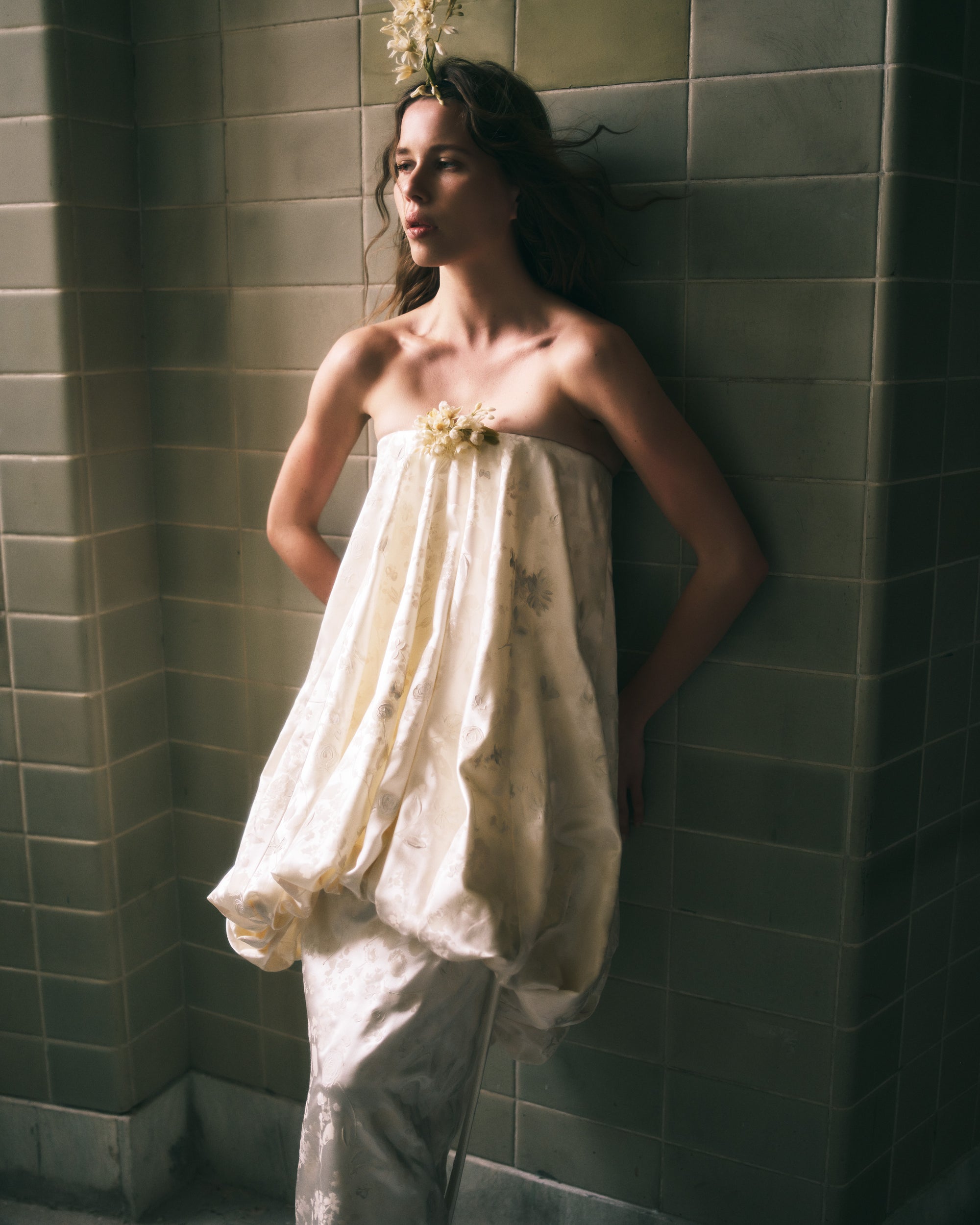 Floral pigment printed and handpainted silk wool strapless column gown. Elongated bubbled bodice overlay falls from neckline ending in a corded channel detail at low hip. Covered button closure down center back, boned internal bustier, internal grosgrain belt and invisible zip closure at center back.