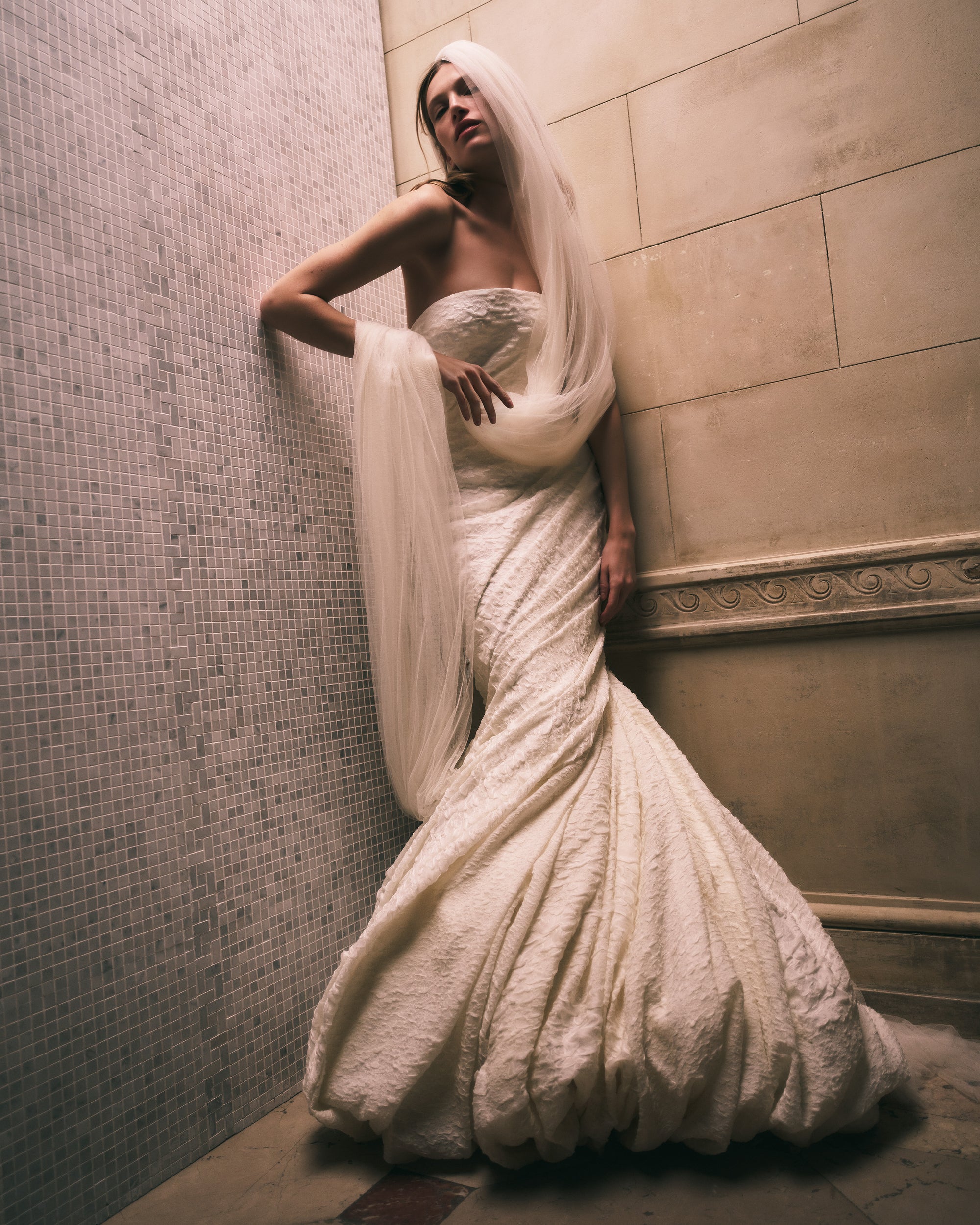 Strapless textured stretch cloqué fluted gown. Twisted drape wraps continuously around the body transcending into a dramatic bubble hem. Boned internal bustier, internal grosgrain belt and invisible zip closure at center back.